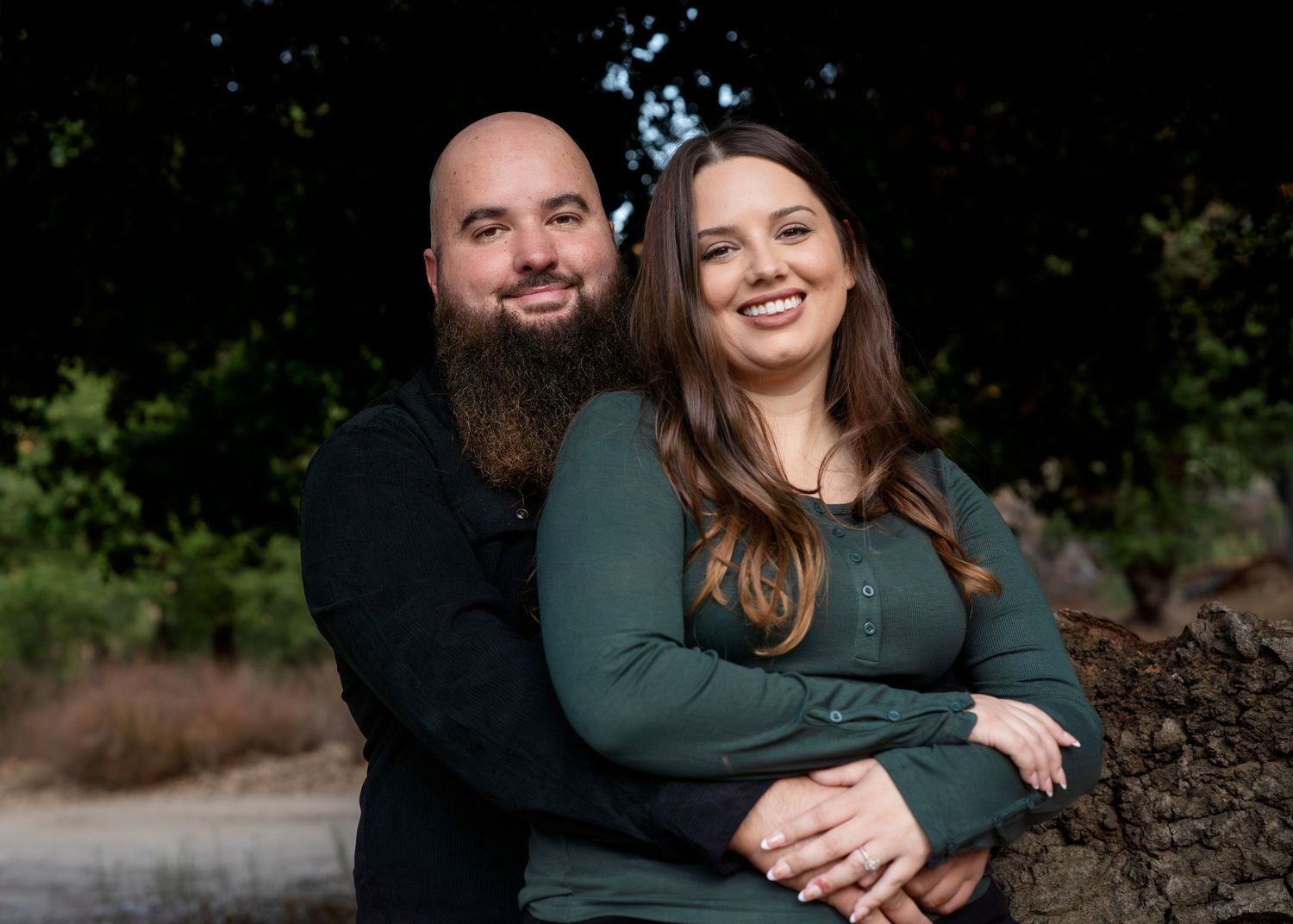 Couple sharing tender moment outdoors wearing matching dark tops.