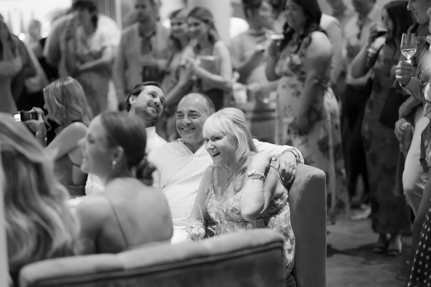 Wedding guests laugh and celebrate together during outdoor reception ceremony.