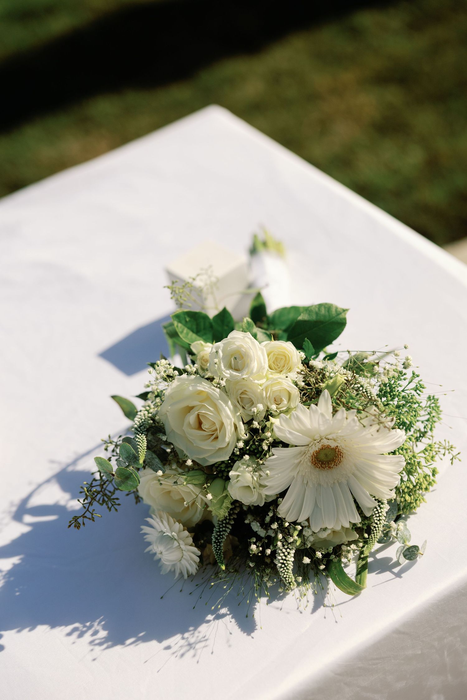 White rose and gerbera daisy bridal bouquet on white tablecloth at wedding.