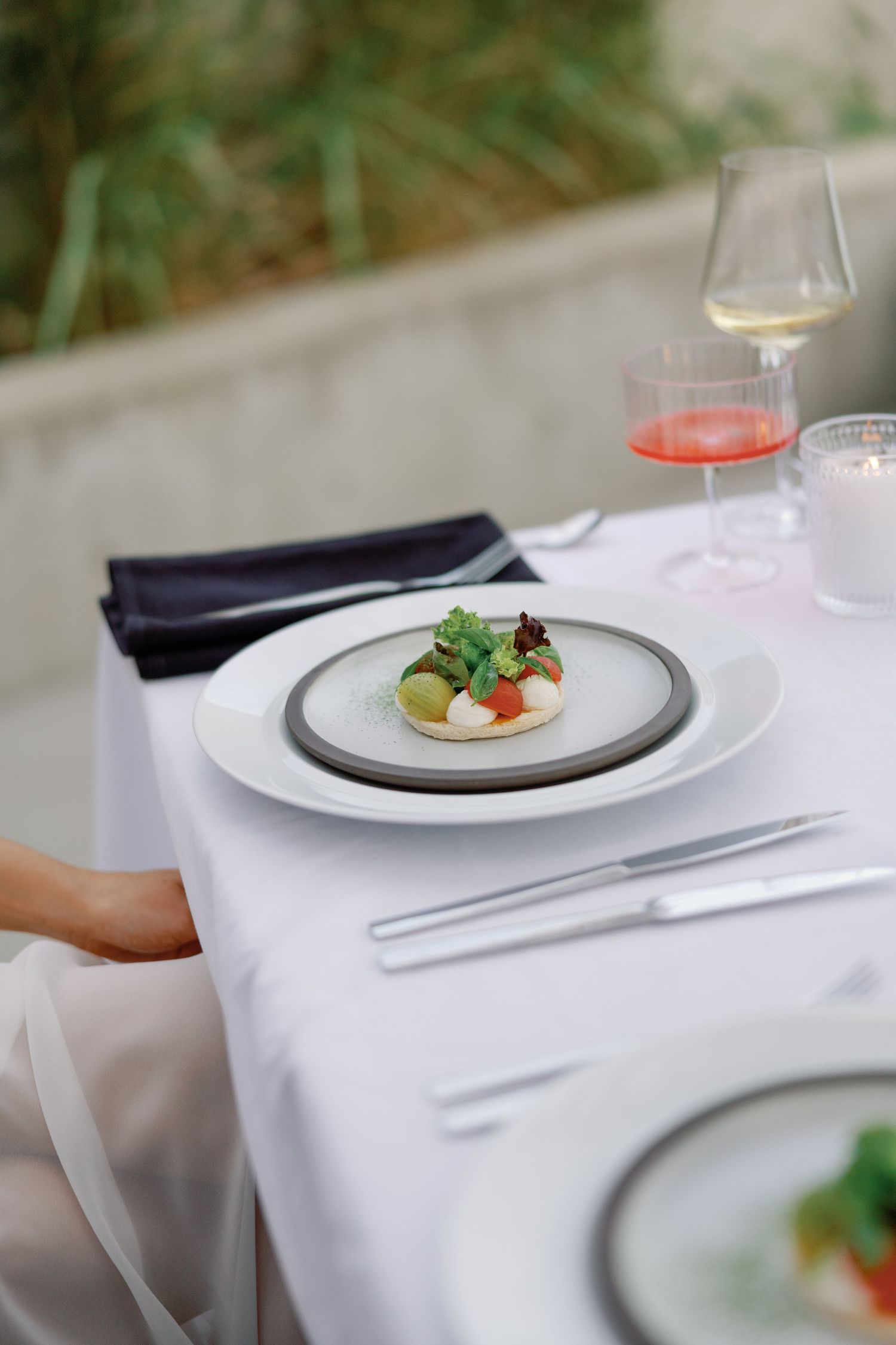 Elegantly plated gourmet dish with fresh garnish served on white linen tablecloth with wine glasses at wedding reception.