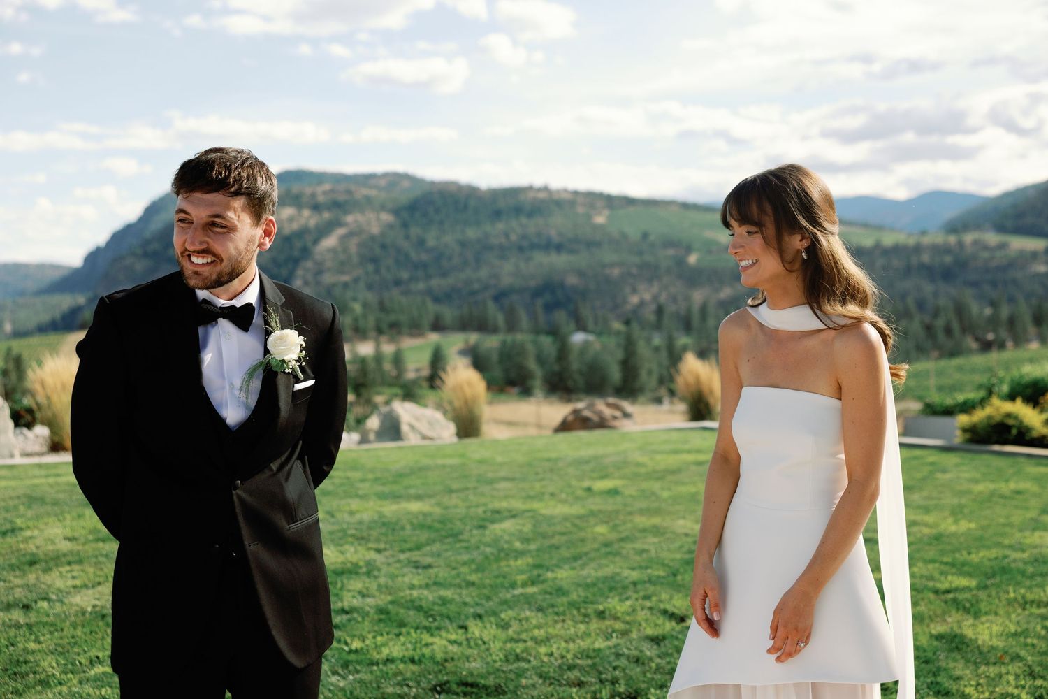 Bride and groom sharing a joyful moment outdoors with stunning mountain valley backdrop.