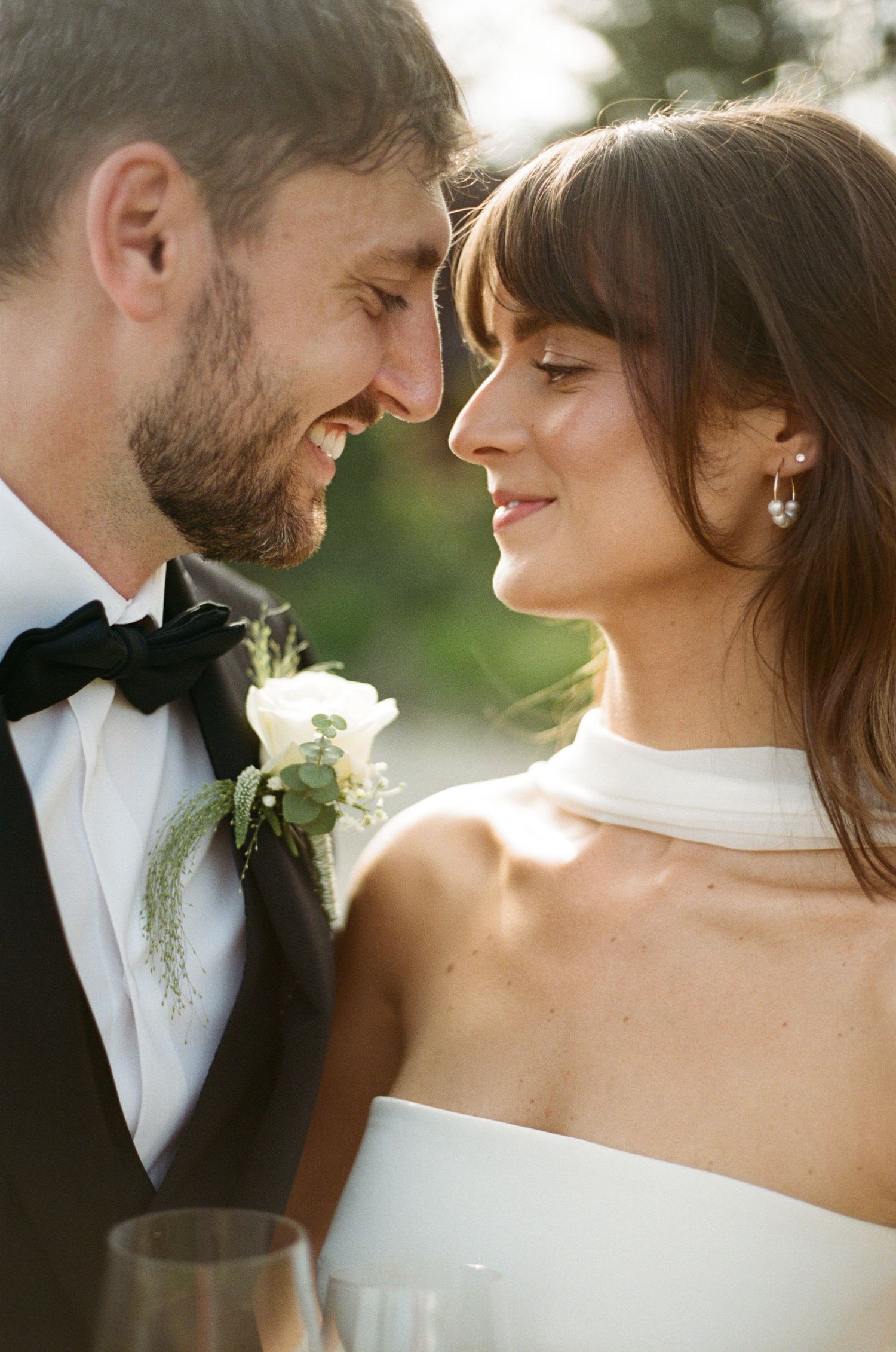 Bride and groom sharing an intimate moment, touching foreheads and smiling at outdoor vineyard wedding.