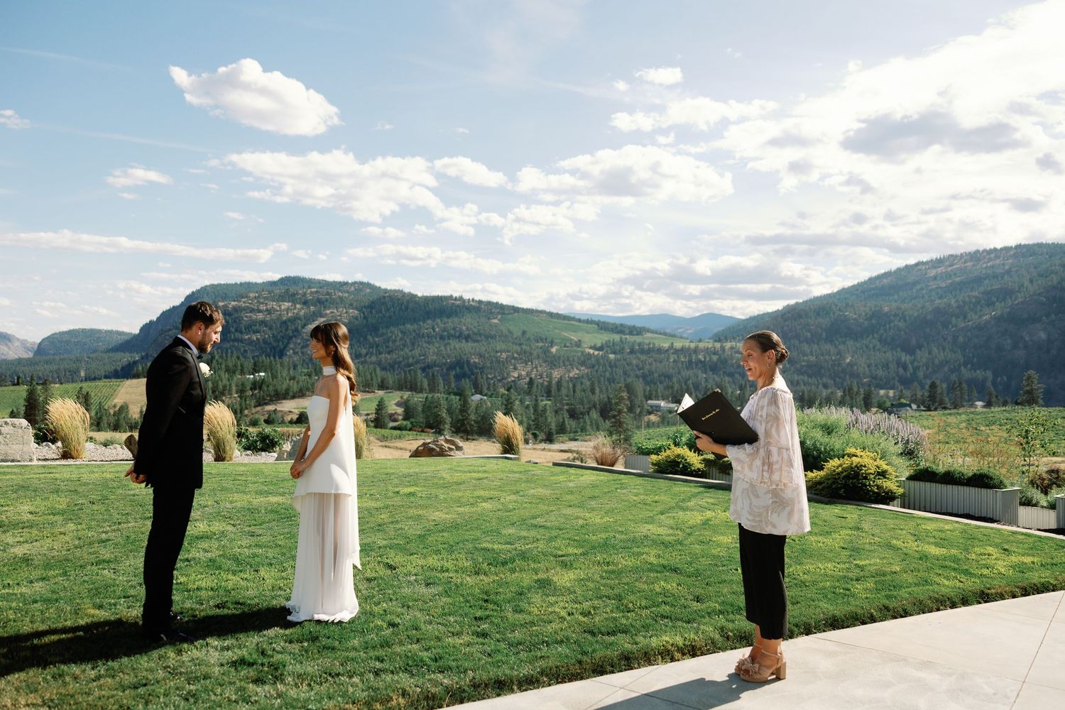 Officiant leads intimate outdoor wedding ceremony with mountain views in background.