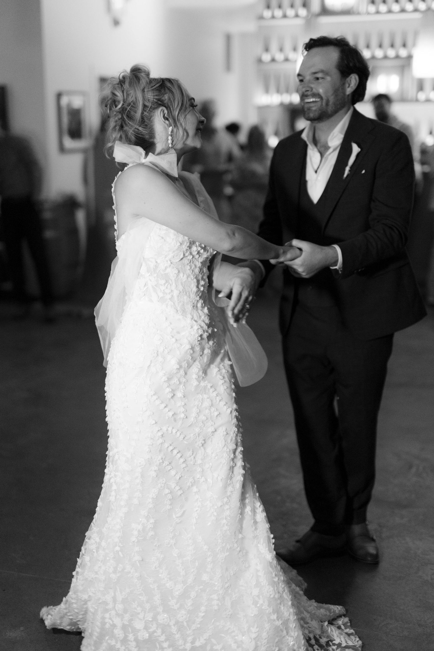 Bride and groom share a joyful first dance in black and white wedding photo.
