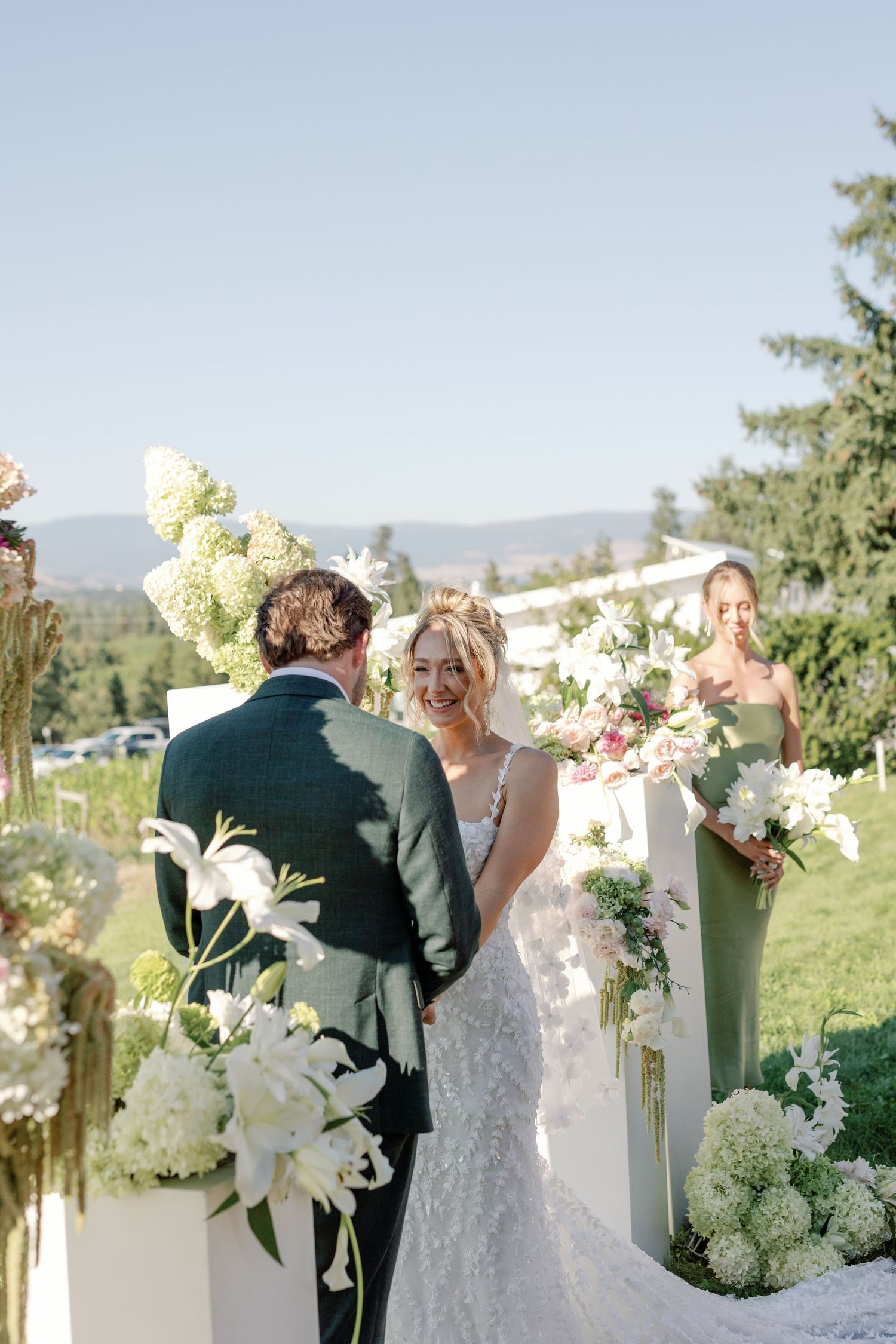 Bride and groom exchange vows at elegant outdoor ceremony with white hydrangea floral arrangements.
