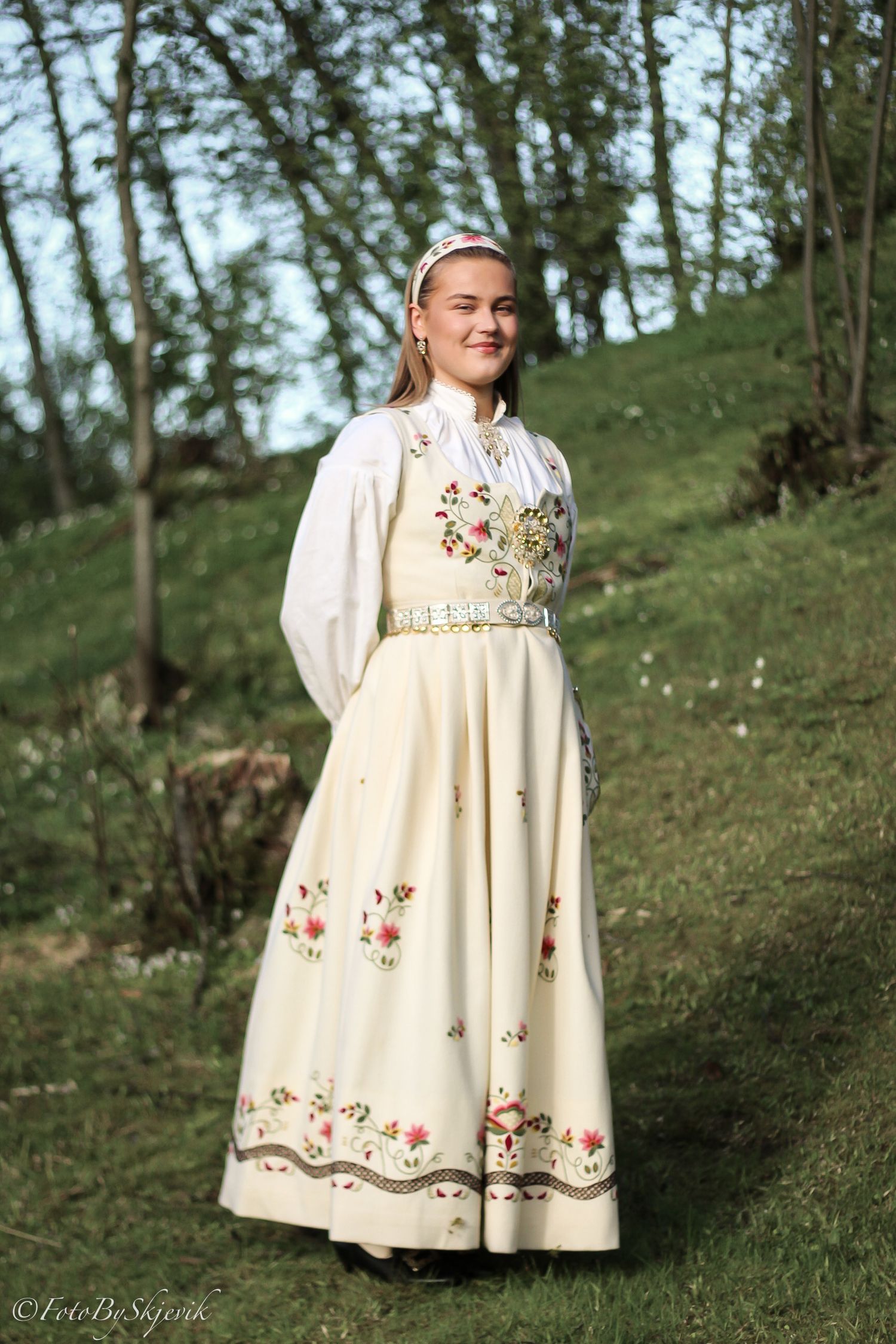 Cream-colored dress with floral embroidery details photographed in natural outdoor setting.