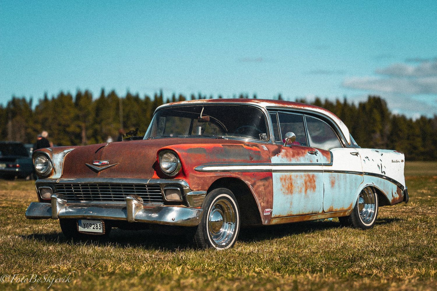 Row of vintage American cars displayed on grass at a classic car meetup.