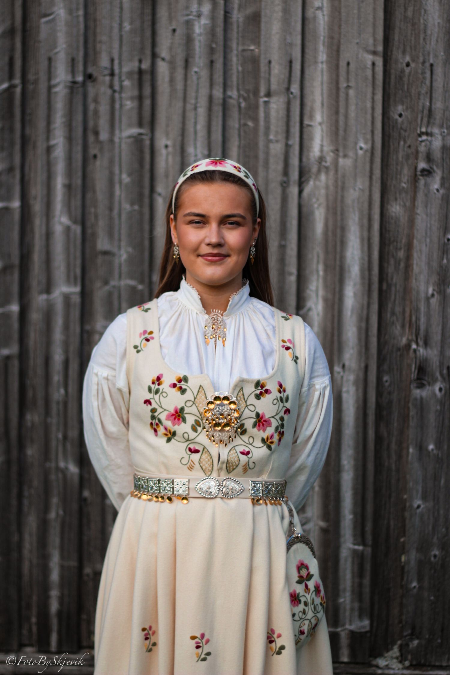 Young woman wearing traditional Norwegian bunad folk costume with floral embroidery and silver details.