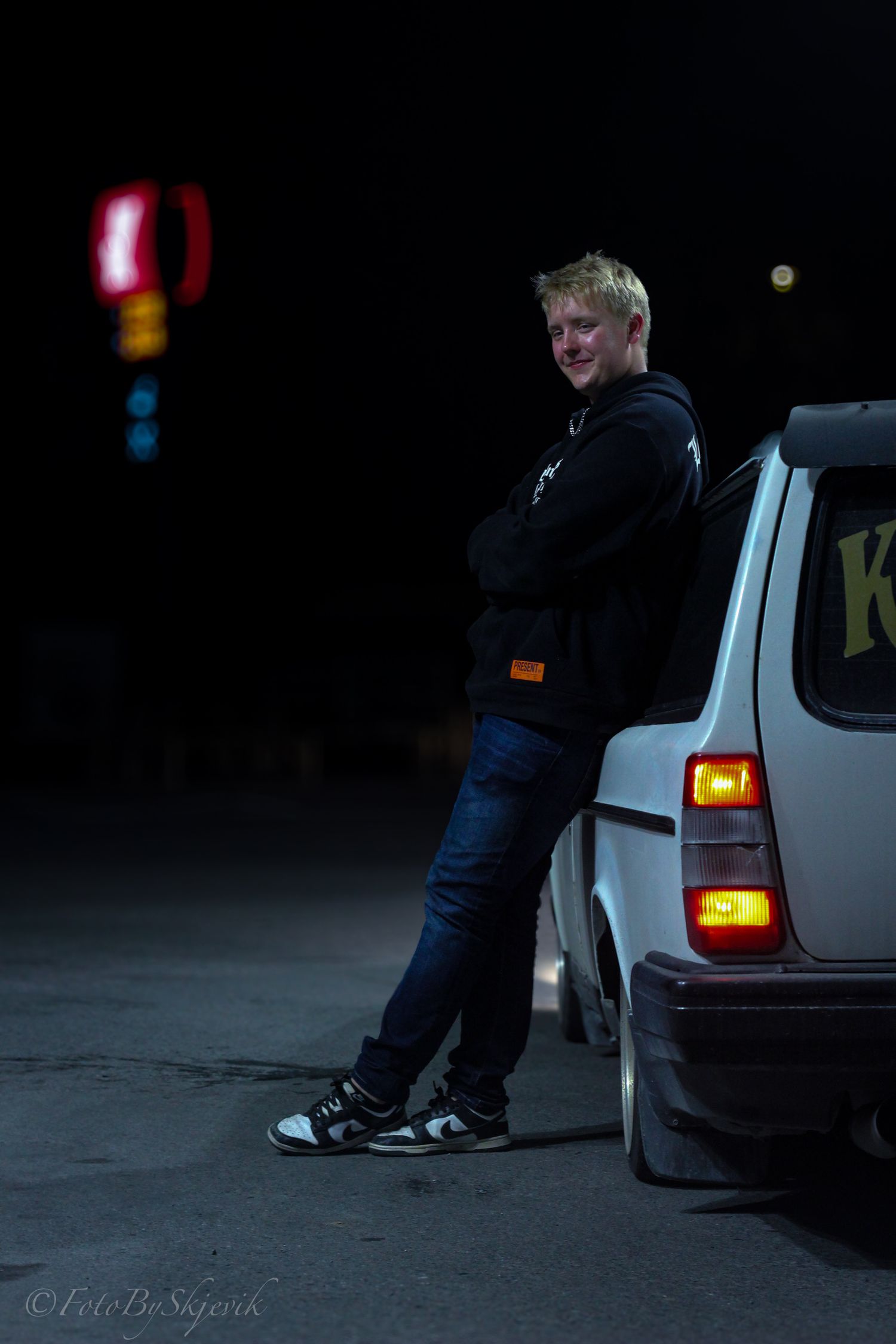 Dark nighttime scene with car taillights glowing in a parking area.