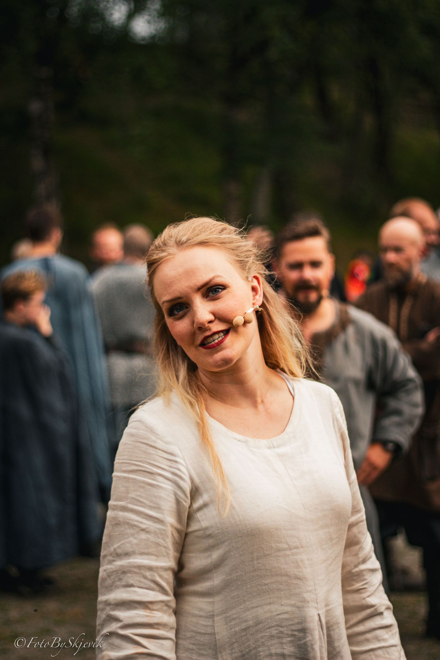 Person in white clothing at outdoor gathering with natural background.