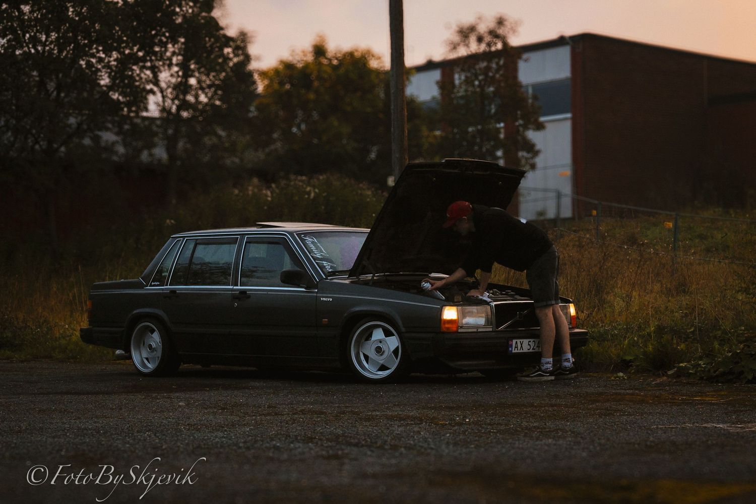 Row of classic black Volvo cars parked at dusk with moody lighting.