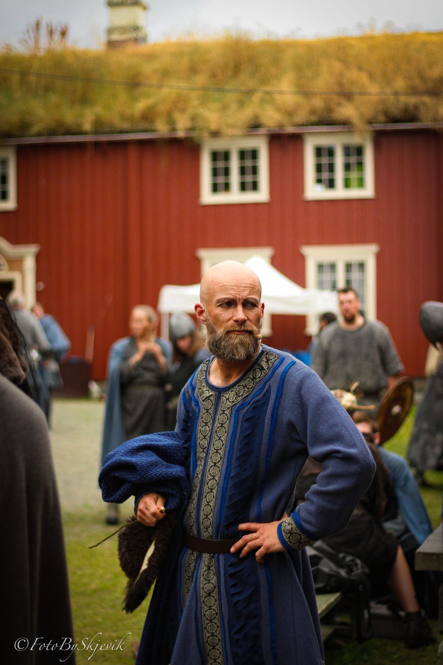 Person wearing an ornate blue medieval-style robe performs at a cultural festival.
