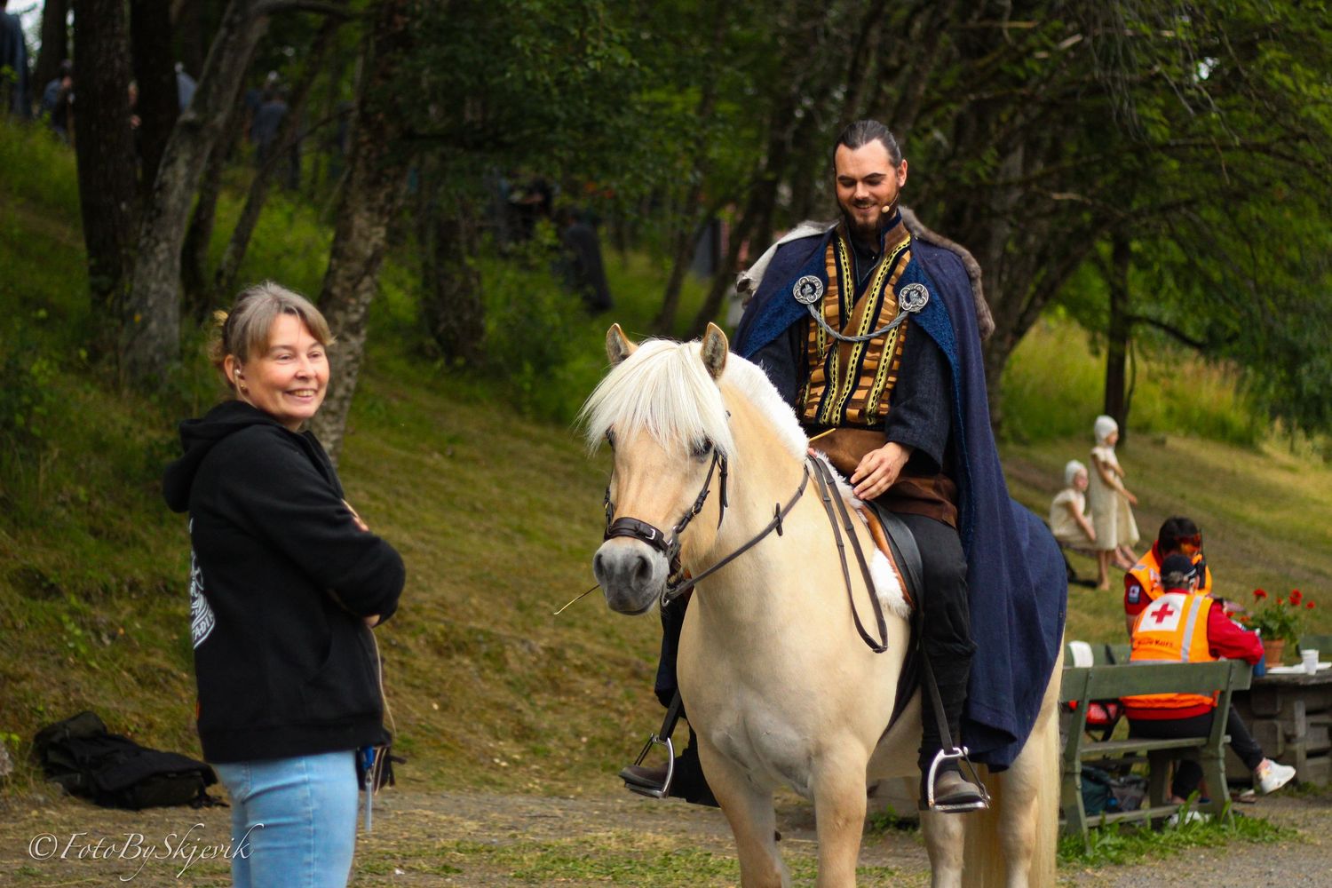 White horse and riders enjoy an autumn day at an outdoor event.