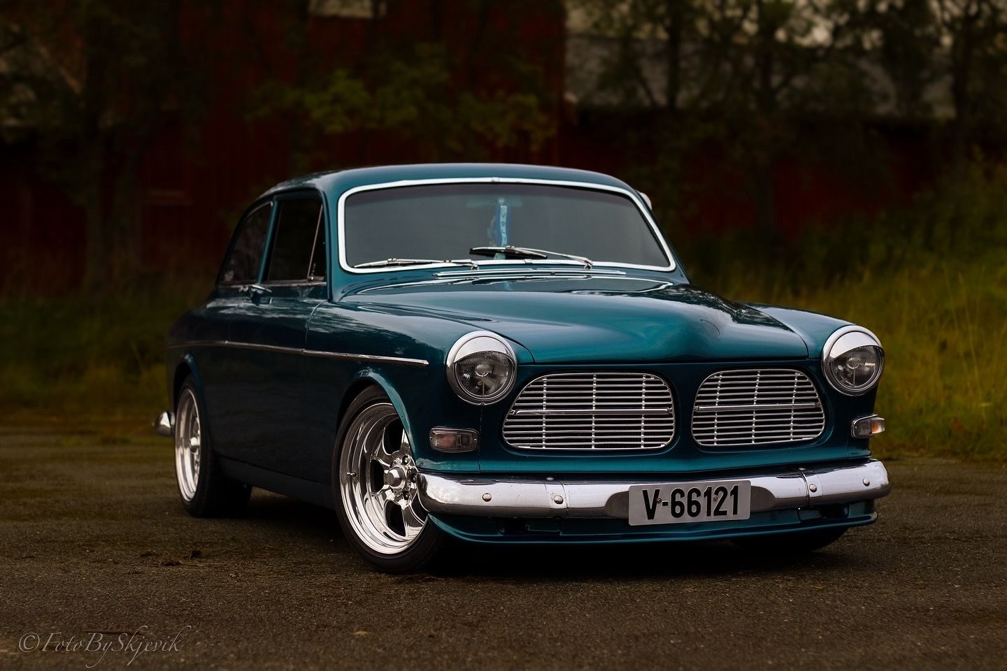 A beautifully restored classic Volvo in dark turquoise with chrome trim and custom wheels.