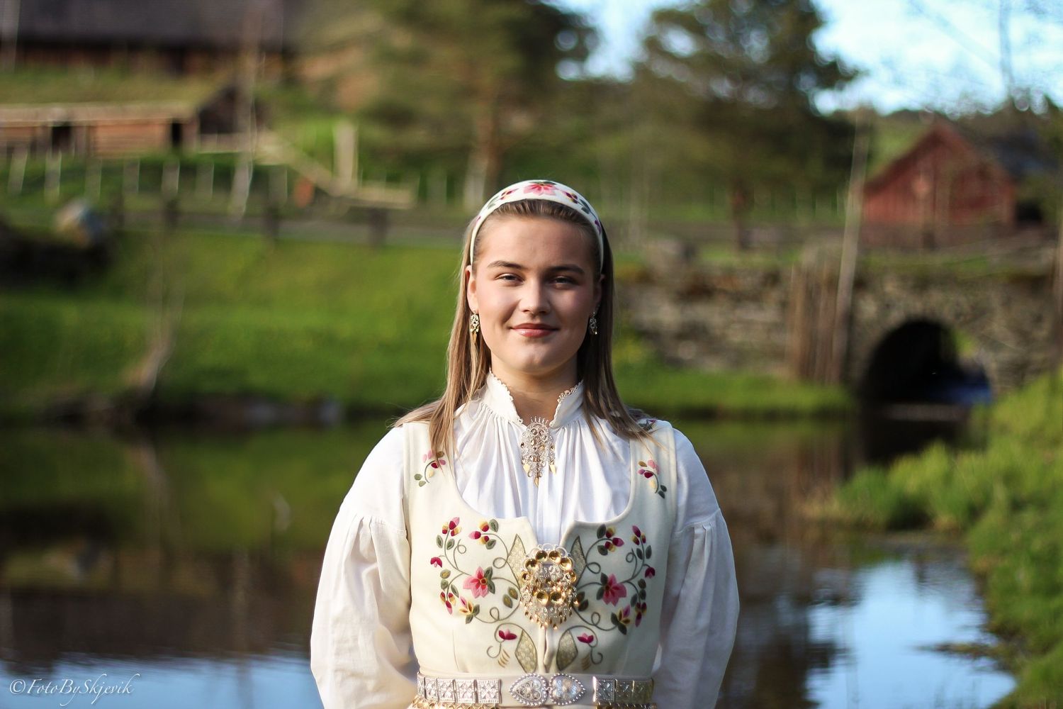 Scenic outdoor portrait session by a reflective pond with spring greenery in the background.