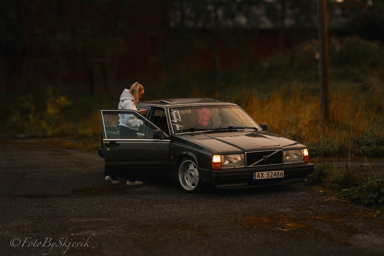 A black Volvo sedan parked at dusk with its door open.