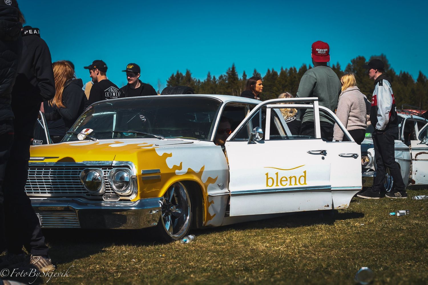 Classic cars lined up at an outdoor car show with mix of white and colorful vintage vehicles.