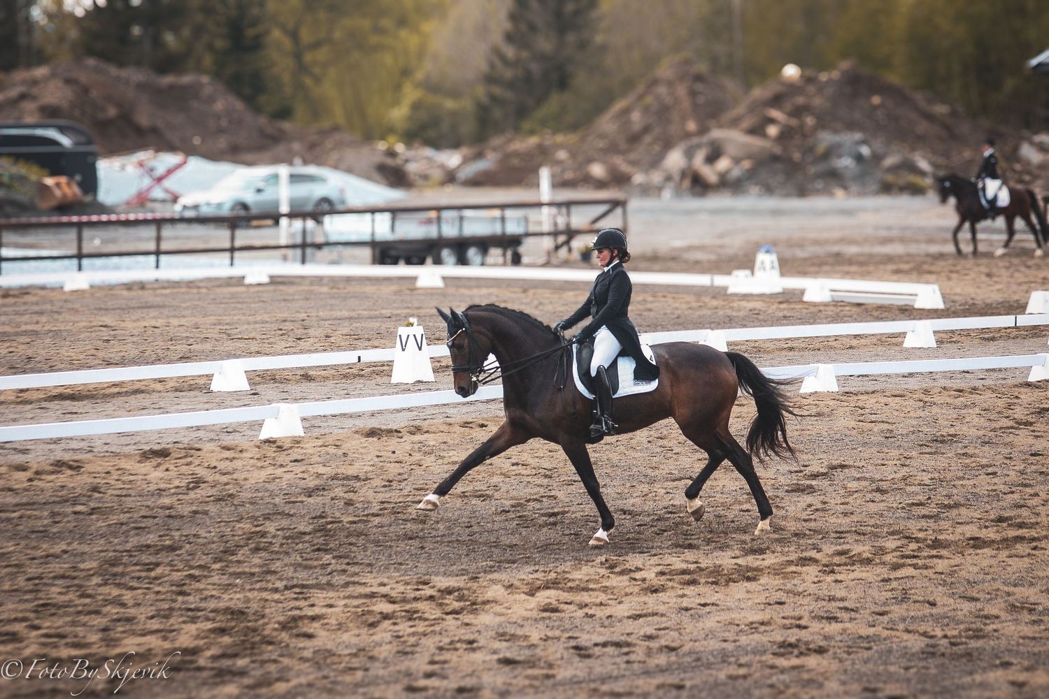 Horses and riders practicing dressage movements in a sandy outdoor arena.