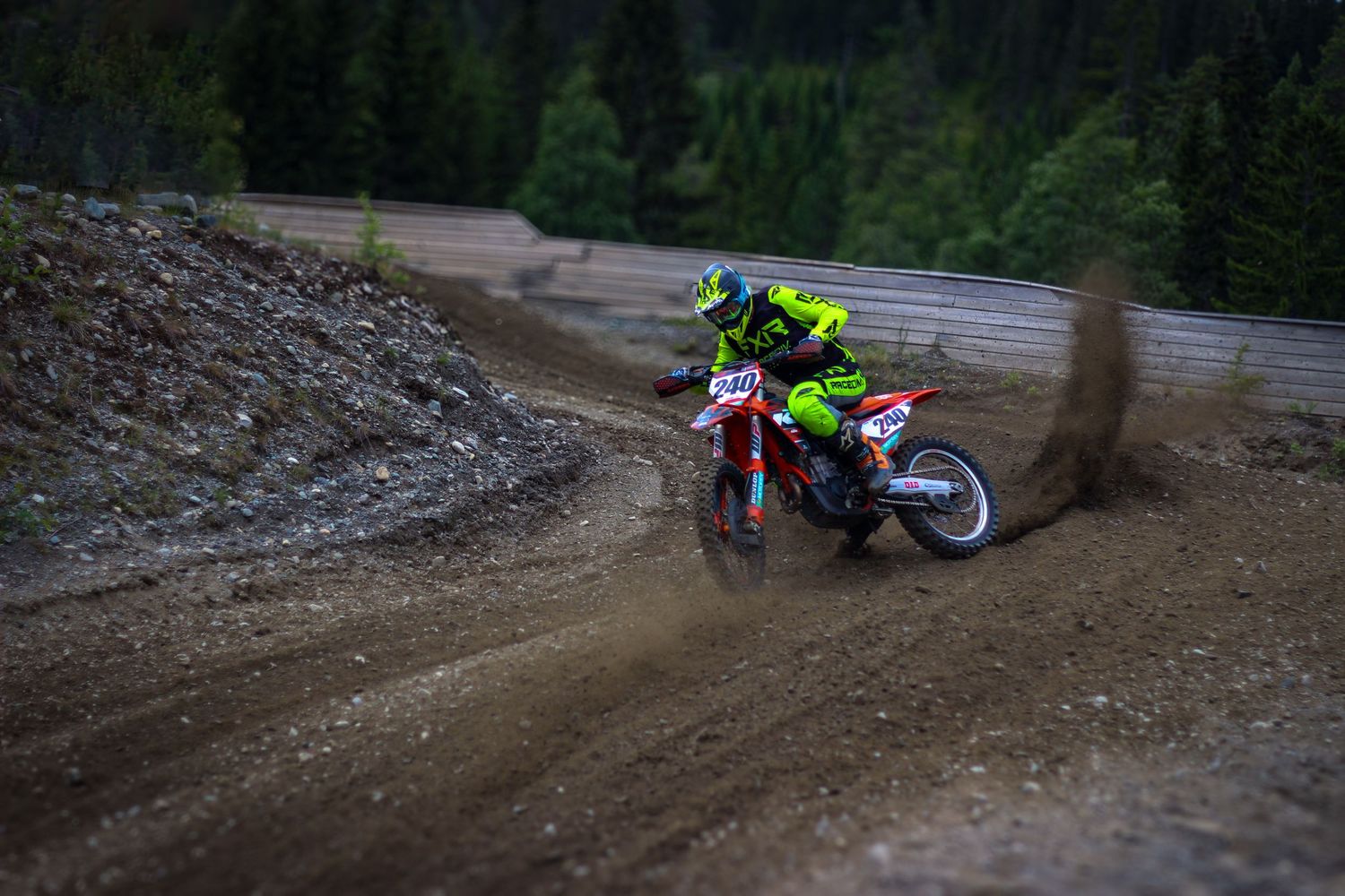 Motocross riders racing through a forested dirt track course.