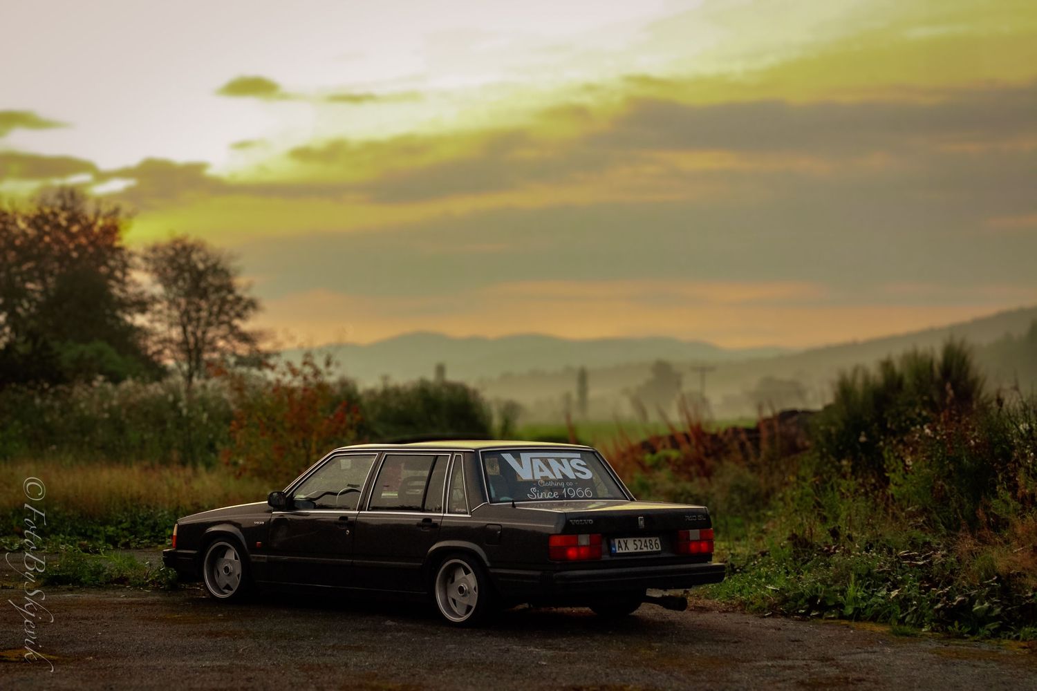 Vintage cars lined up at sunset against a scenic rural backdrop.