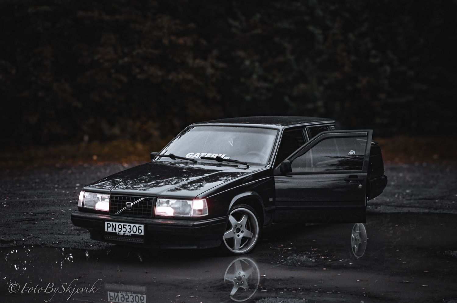 A black Volvo 850 sedan photographed in the rain with its door open.