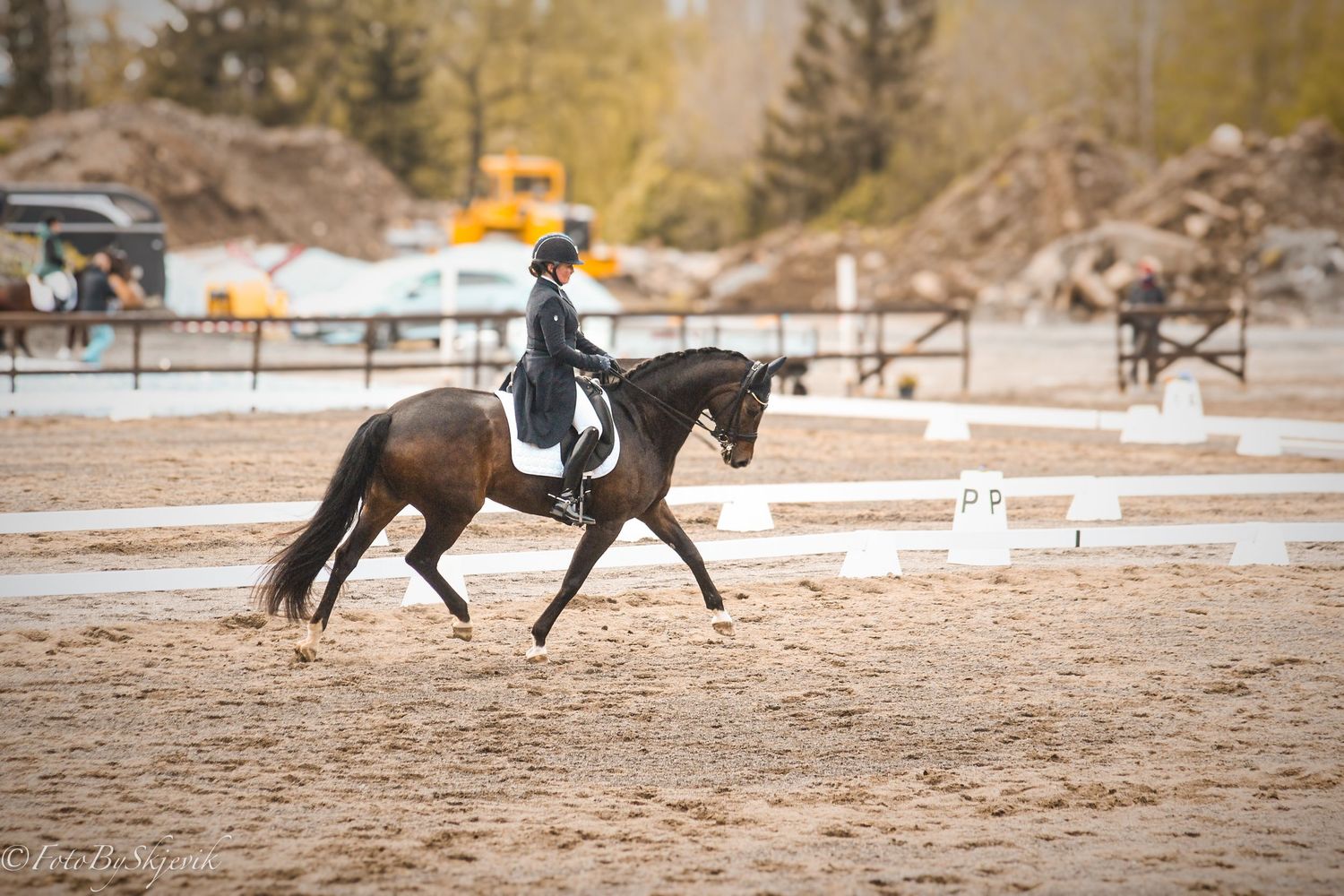 Horses training in a sandy outdoor riding arena during practice.