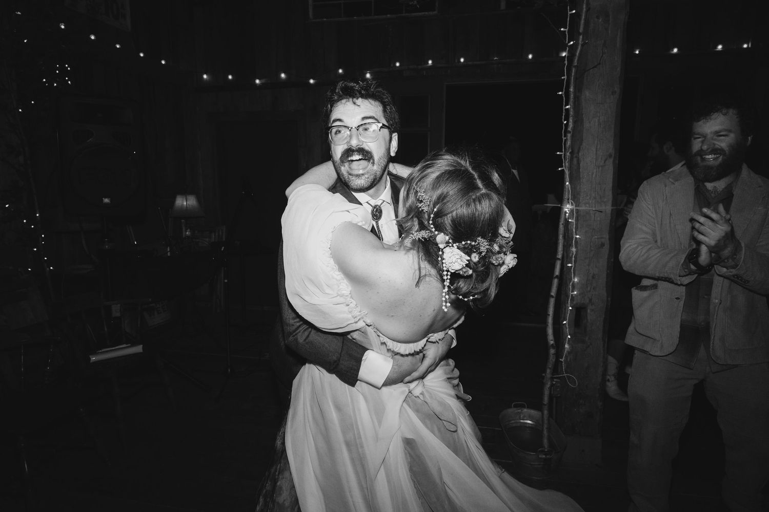 Black and white photo of a bride and groom sharing an emotional first dance embrace at their wedding reception.