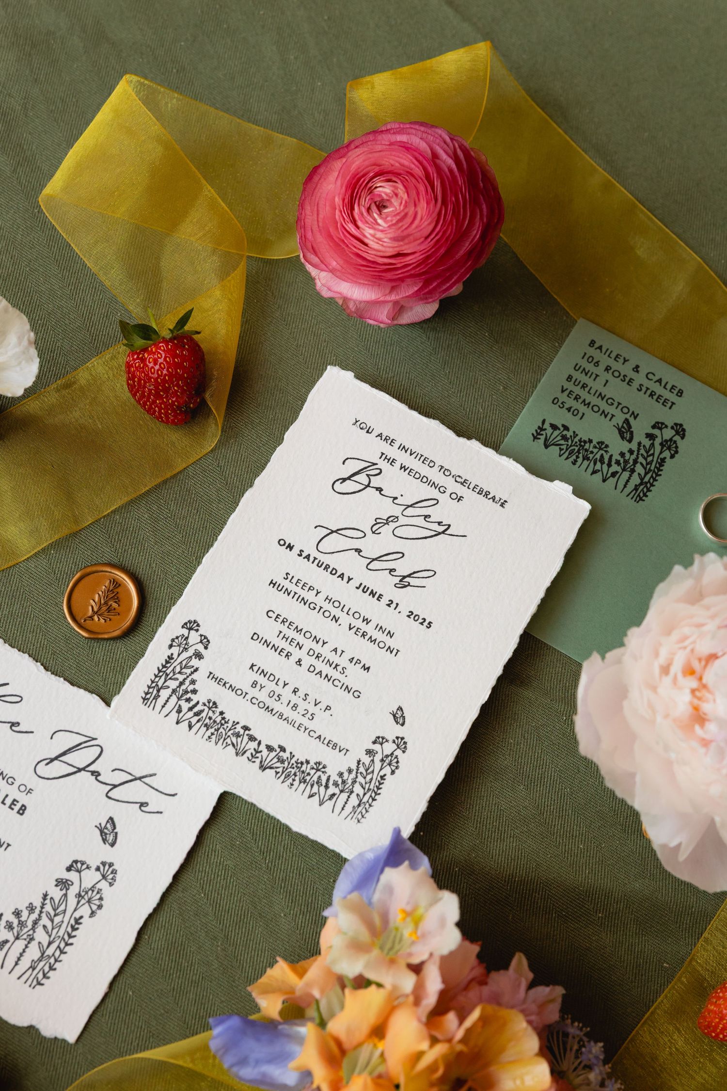 Wedding invitation with pink ranunculus flowers and citrus slices on a dark green background creates an elegant display.