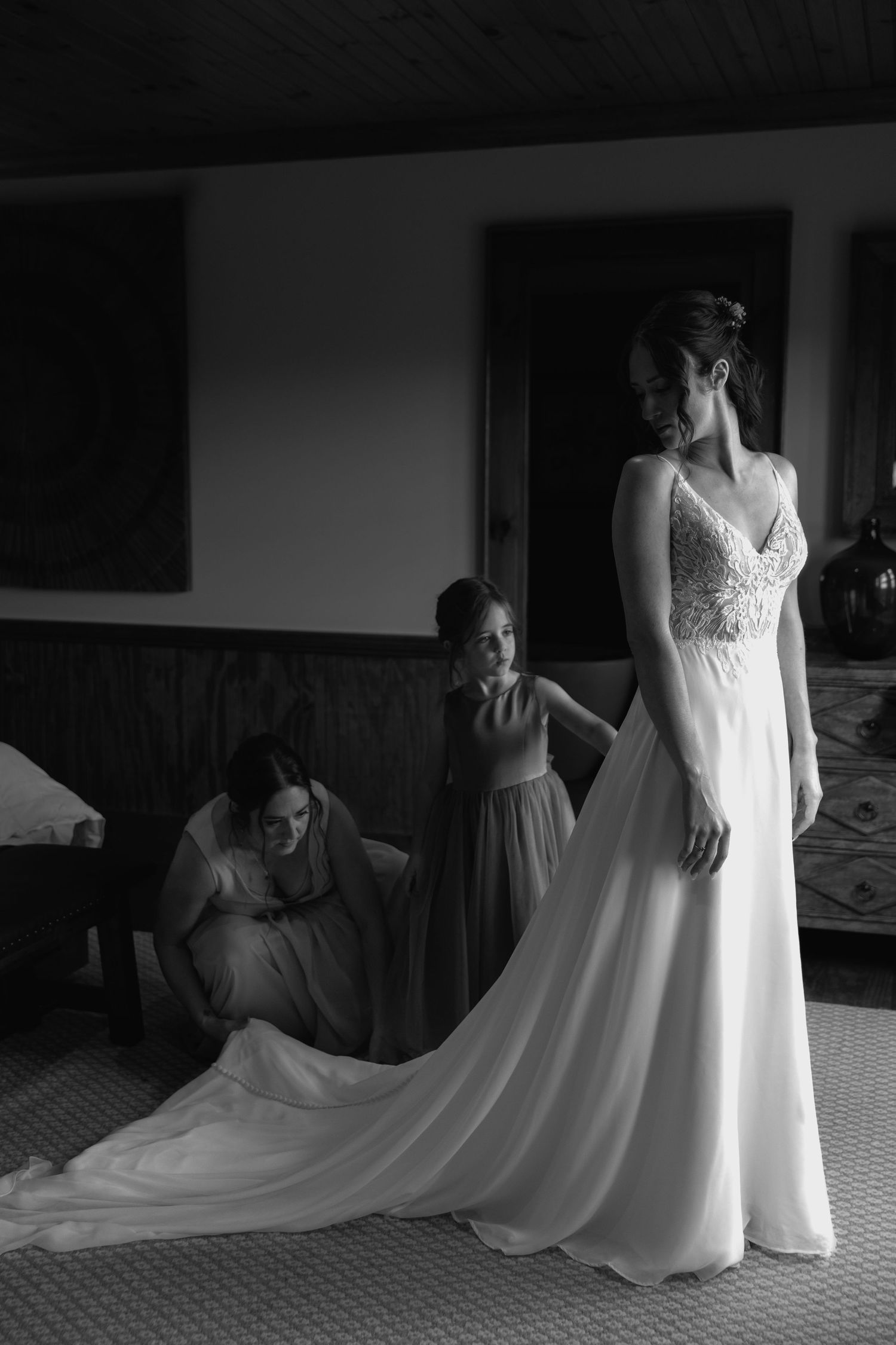 Elegant white wedding gown with lace details and flowing train being fitted.