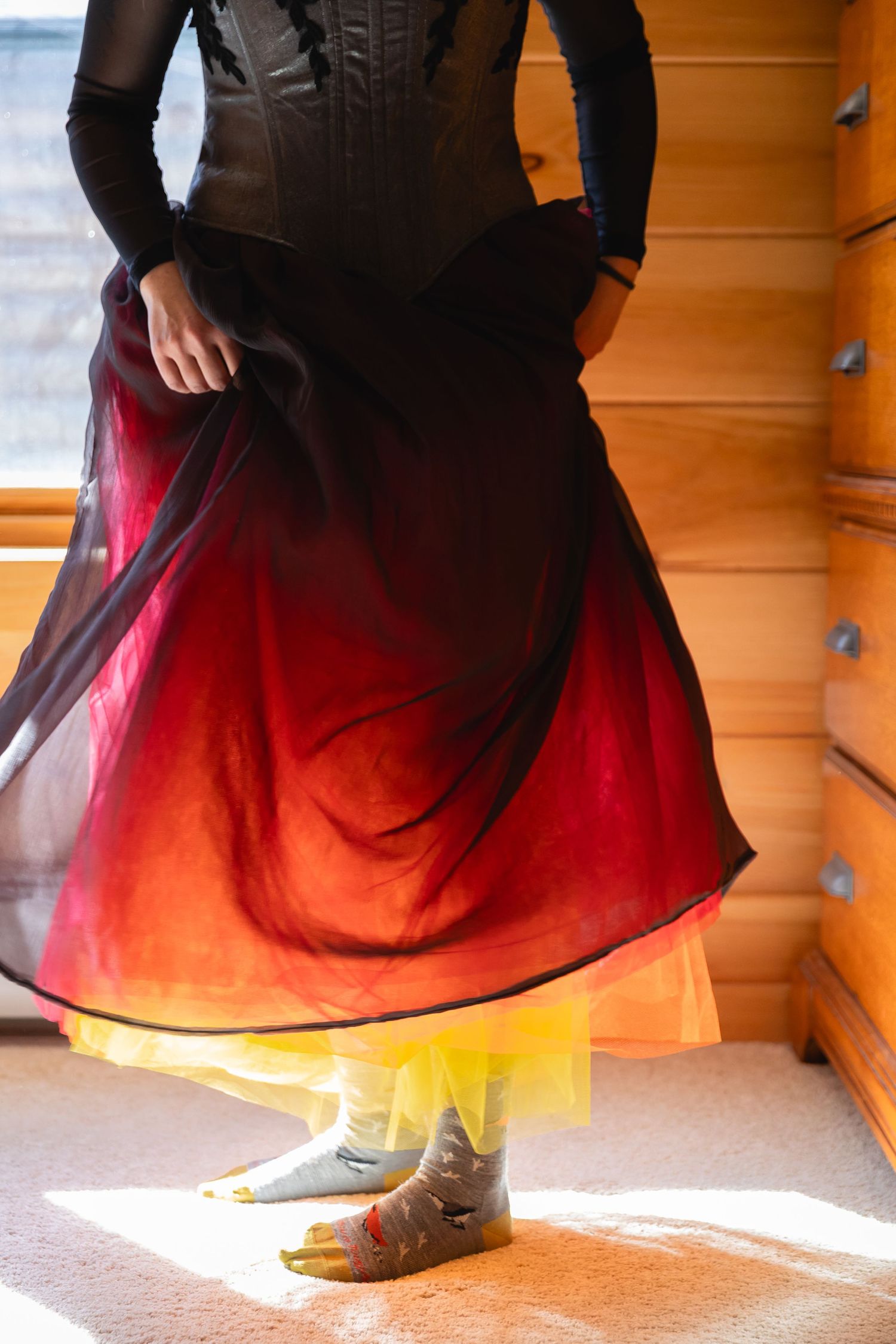A flowing black and red tulle skirt twirls in a sequence of dance movements against an orange background.
