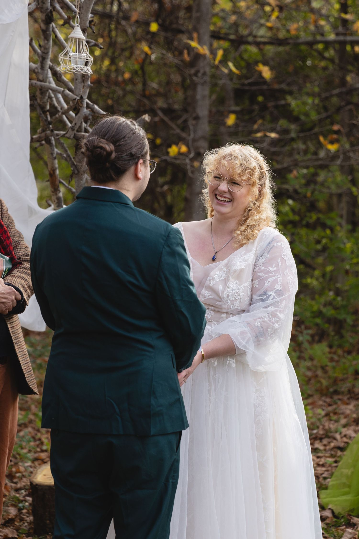 An outdoor autumn wedding ceremony with a decorative lantern hung between trees.