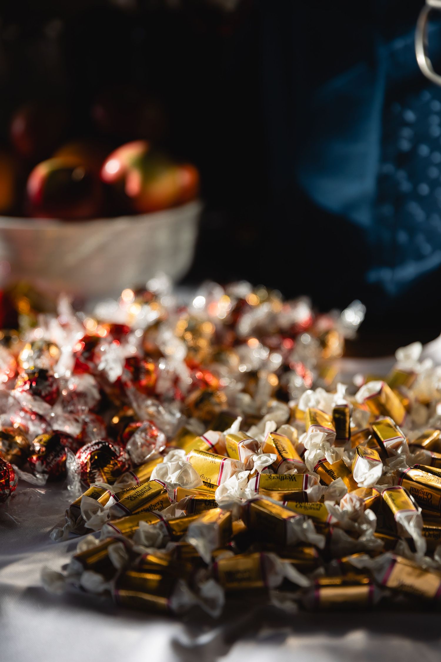 Shimmering metallic gold and silver tinsel garland decorations scattered on a dark surface in moody lighting.