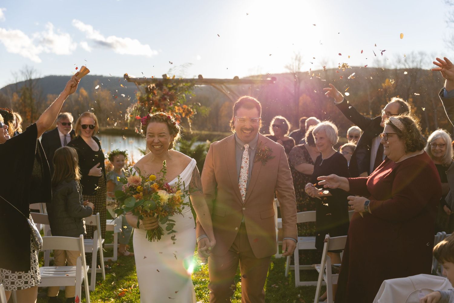 Wedding guests celebrate during a sunny outdoor autumn ceremony with mountain views.
