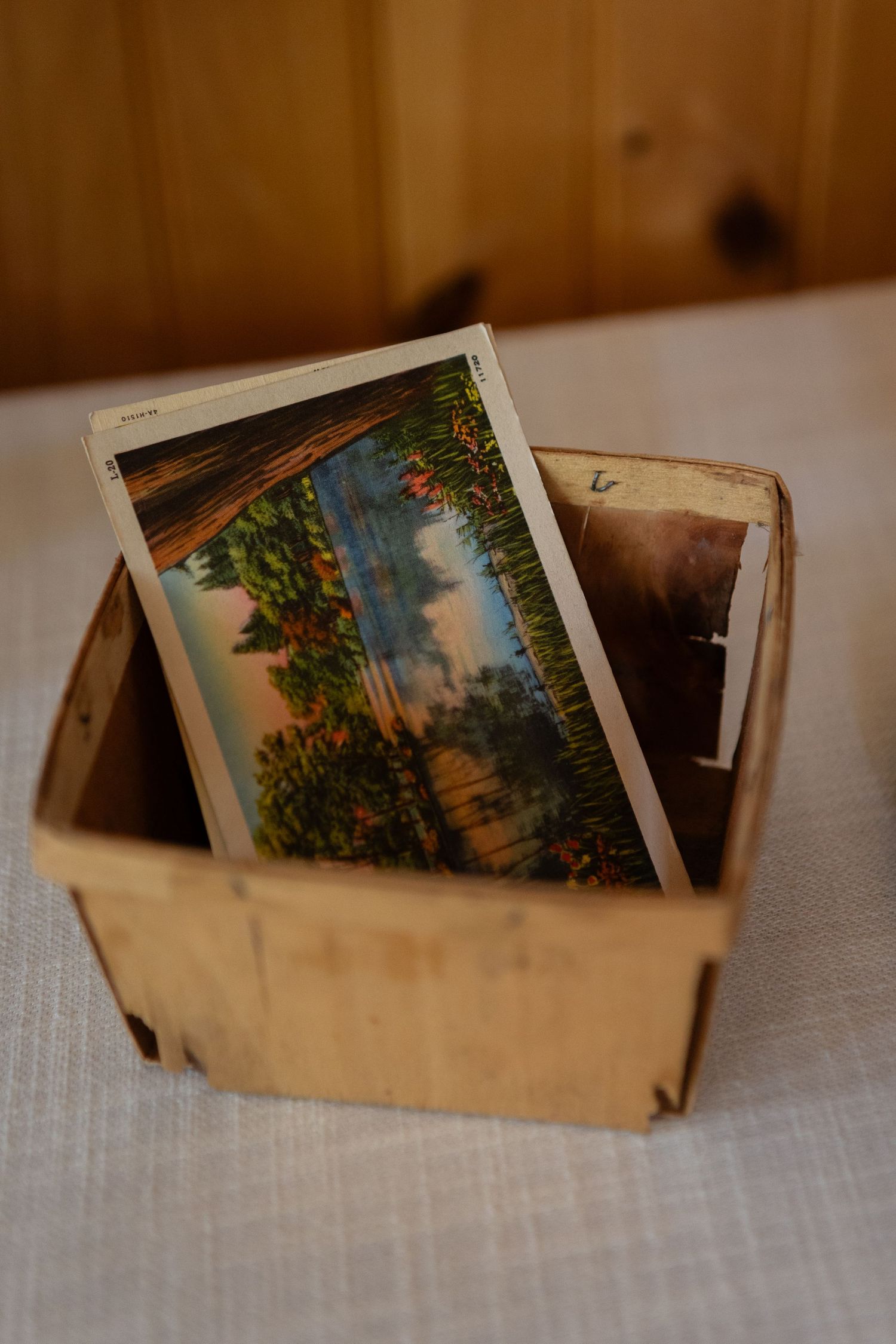 Vintage postcards showing scenic landscapes in a wooden basket.