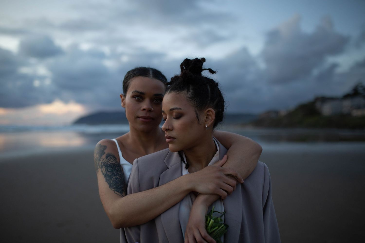 A tender moment between a couple in matching outfits against a dramatic sunset sky.
