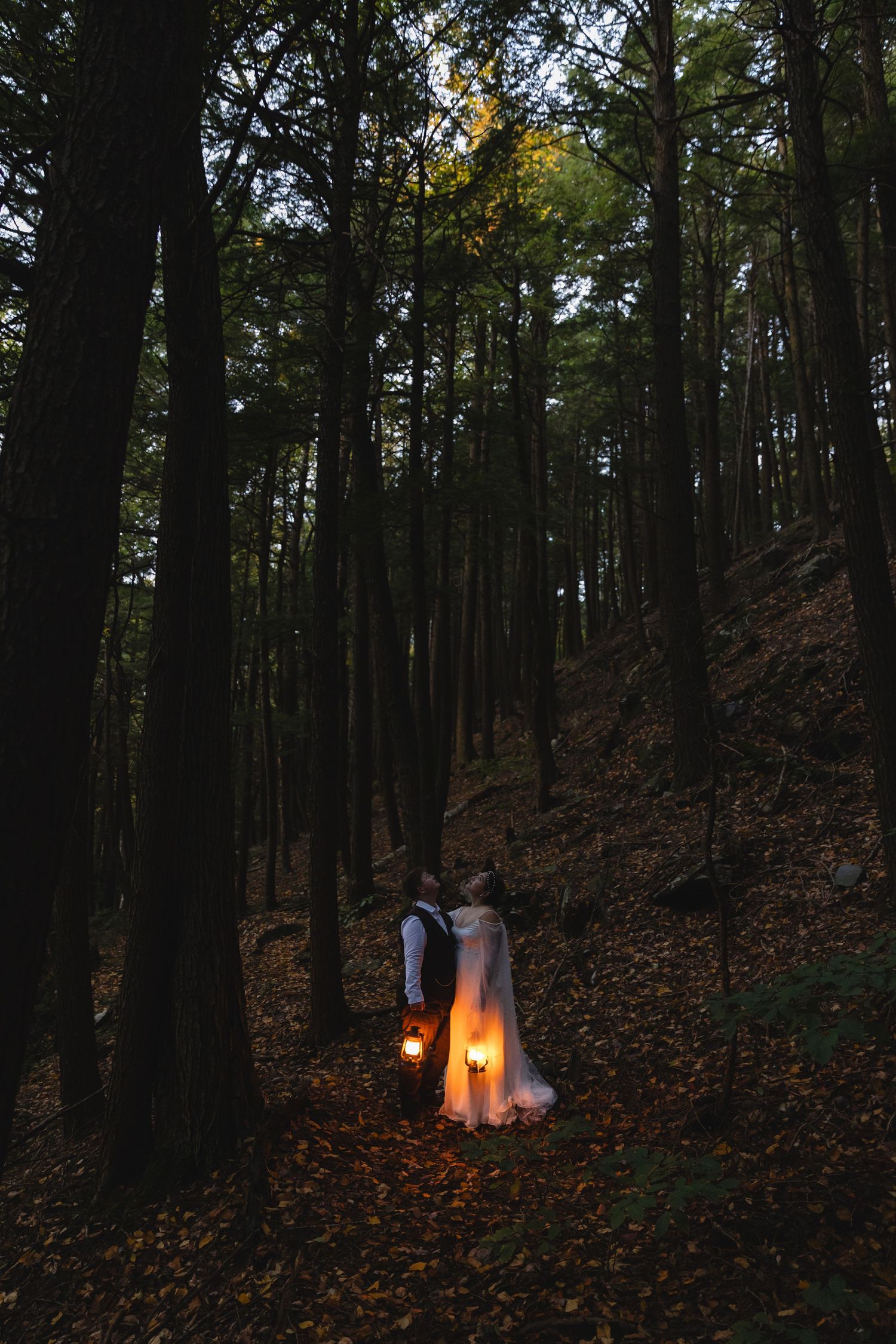 Candlelit wedding scene in a mystical forest with tall trees and fallen leaves.