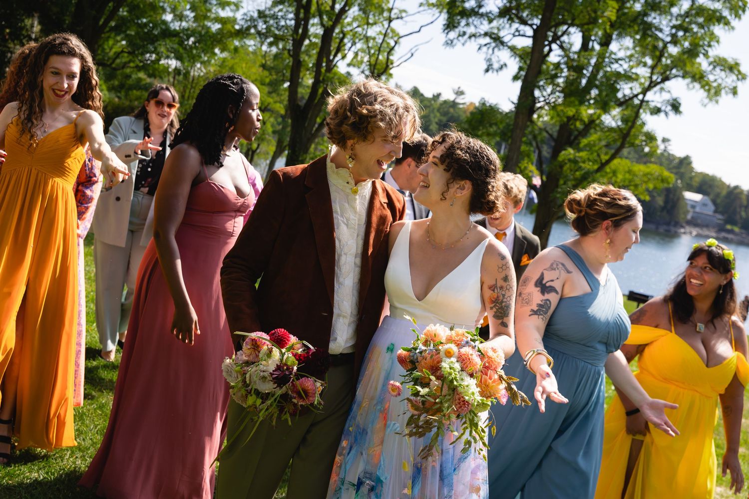 Bride and groom sharing intimate moment surrounded by colorful bridesmaids outdoors.