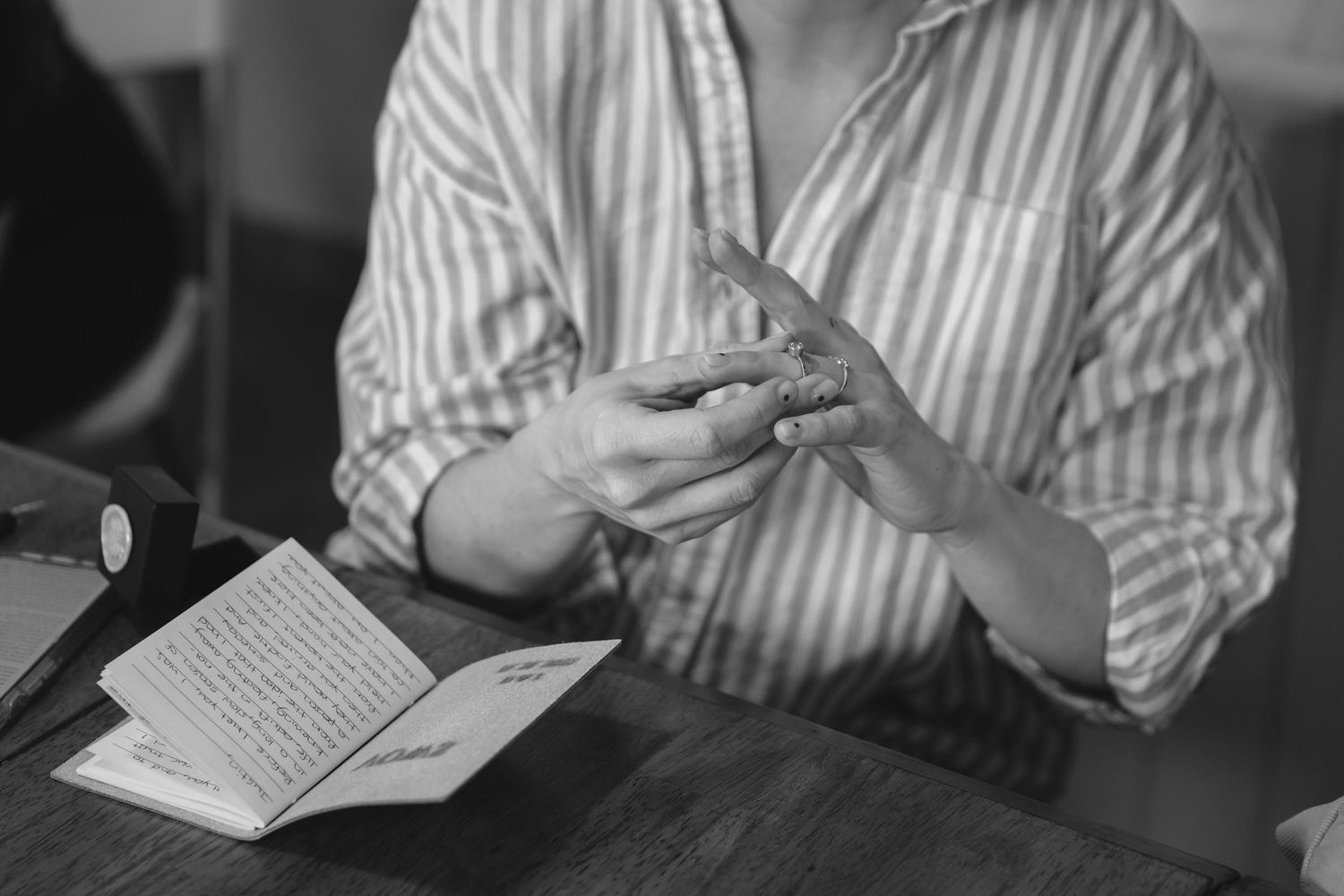 Black and white image of hands holding ring in intimate moment.