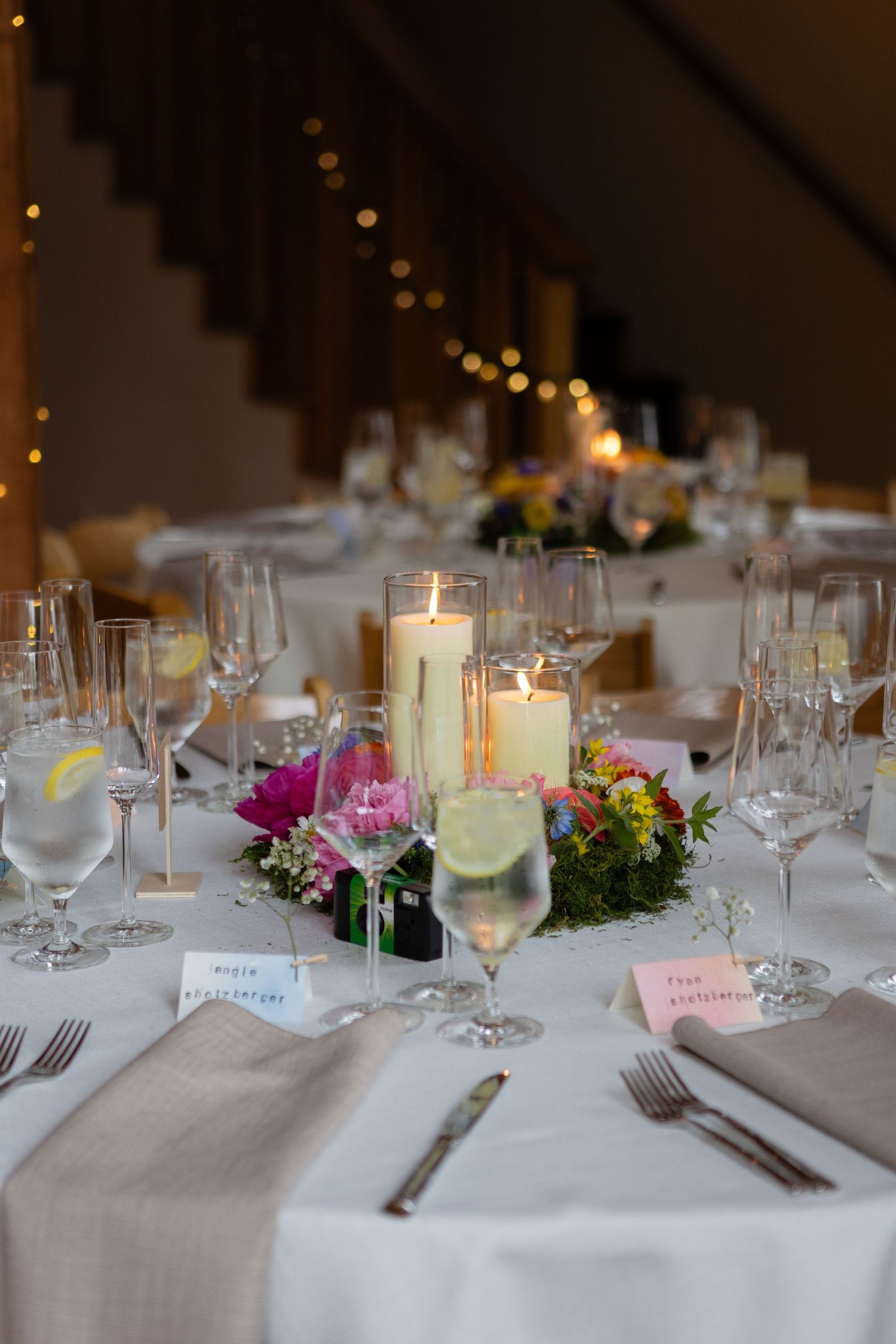 Elegant wedding reception table setting with candles, flowers and wine glasses.