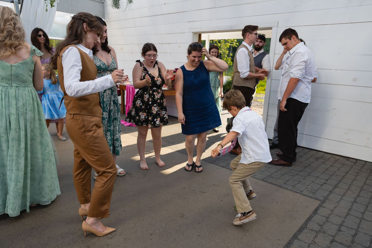 Wedding reception guests forming a dance line on a white-walled patio during a celebration.