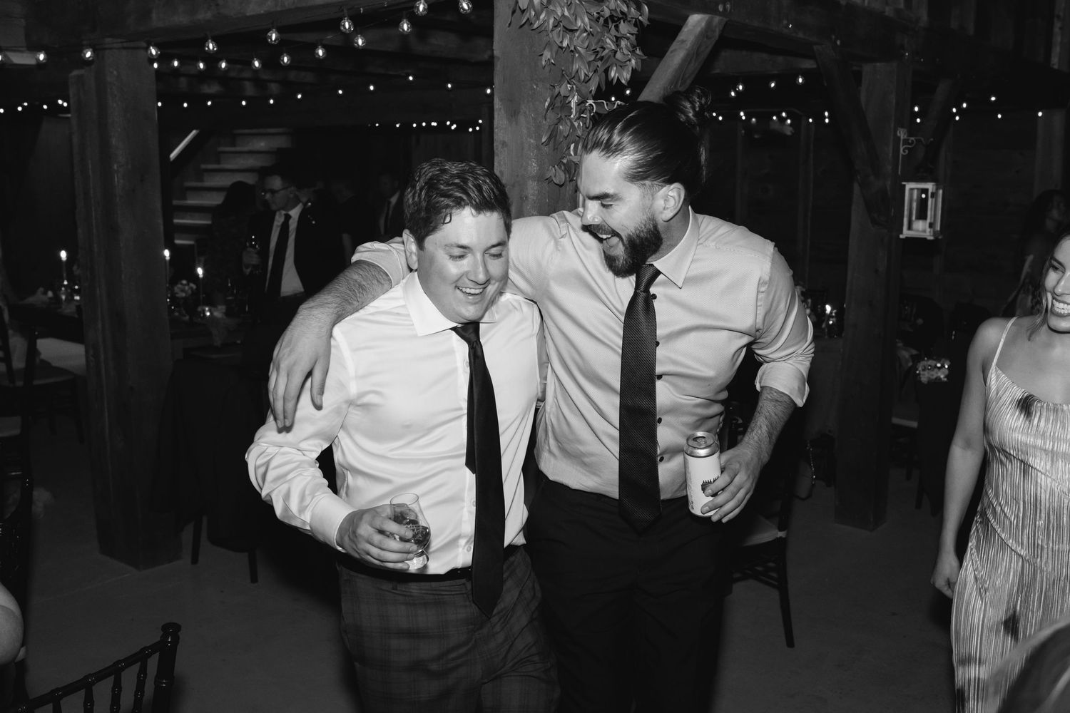 Two guests dancing and smiling together at a wedding reception in black and white.