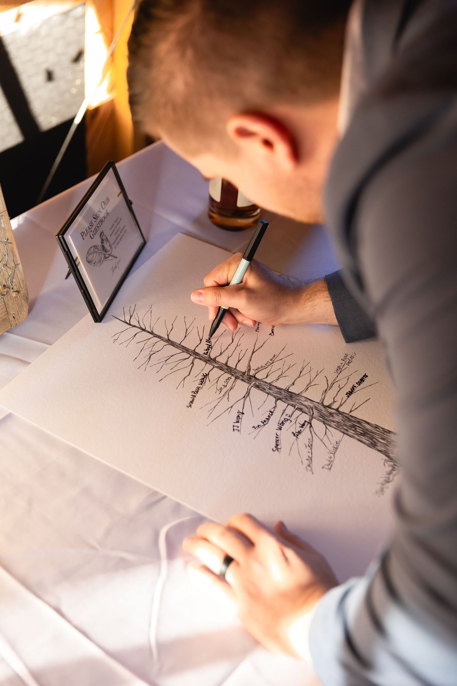 Artist sketches detailed tree reflection drawing with pencil on white paper in warm lighting.