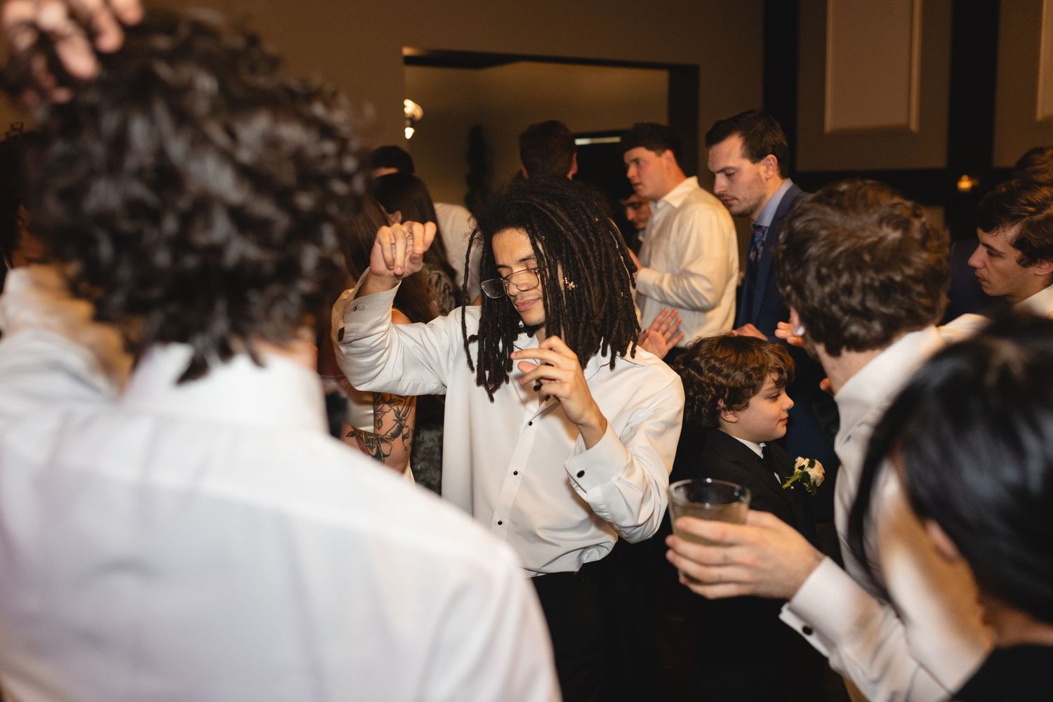 A group of people socialize and laugh together at an indoor event with dim lighting.