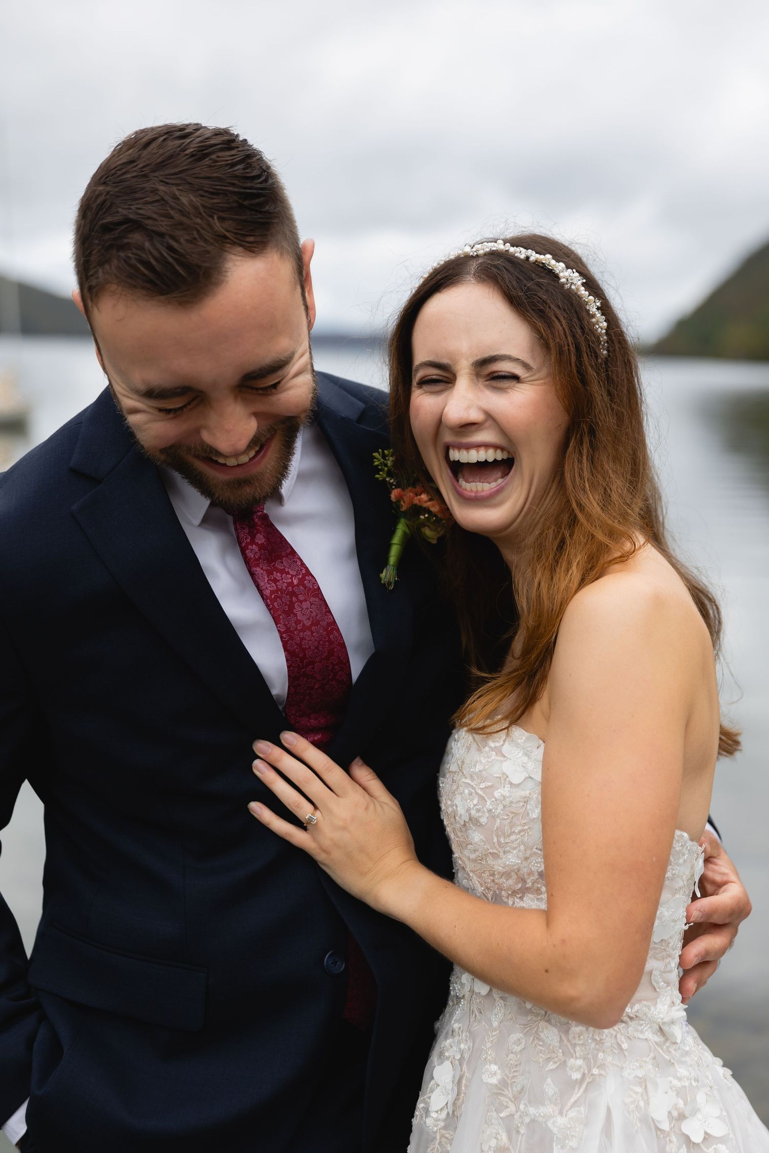 Happy couple sharing a joyful moment by a scenic lake with mountains in background.