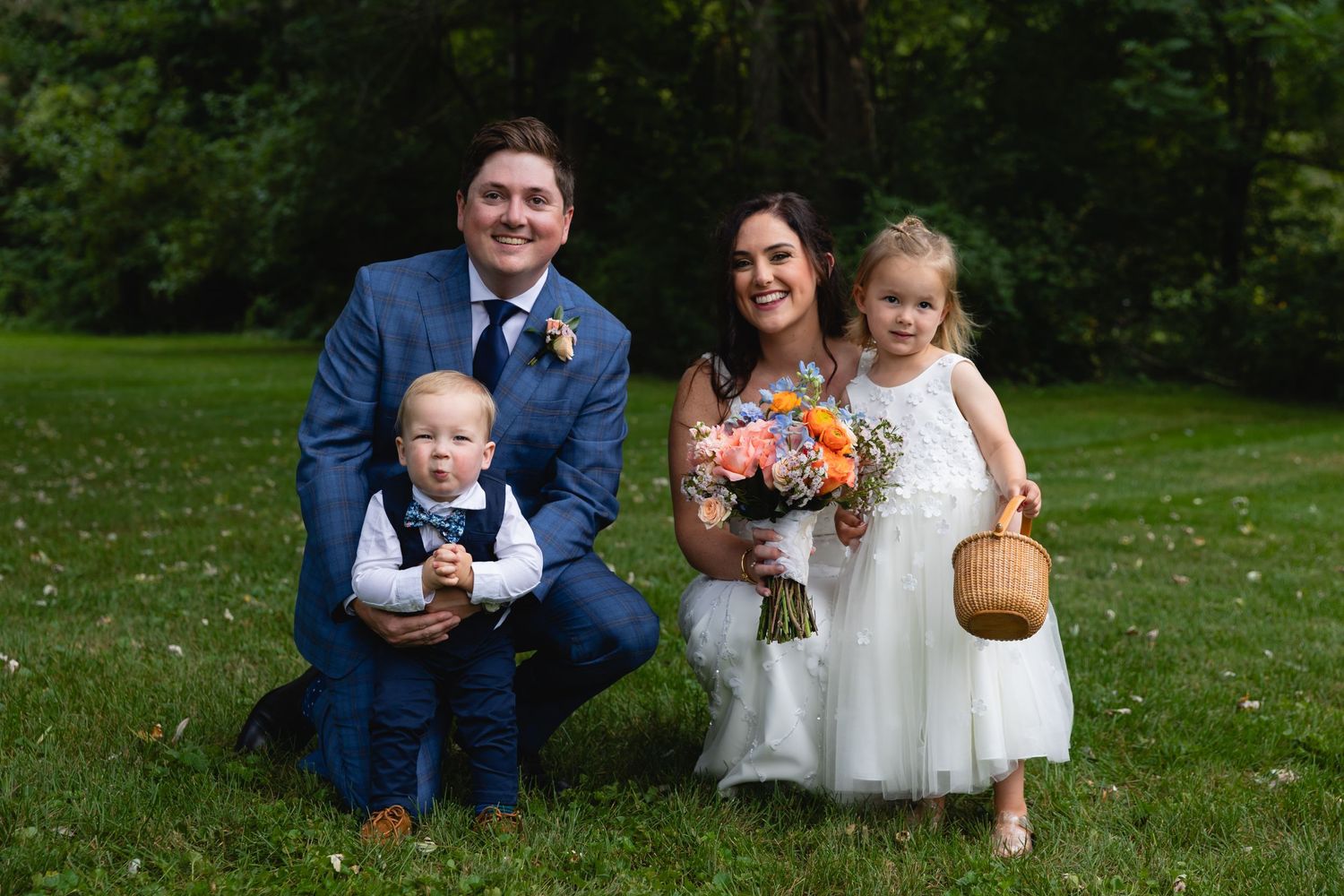 A family poses together on a green lawn during a wedding celebration, with flowers and formal attire.
