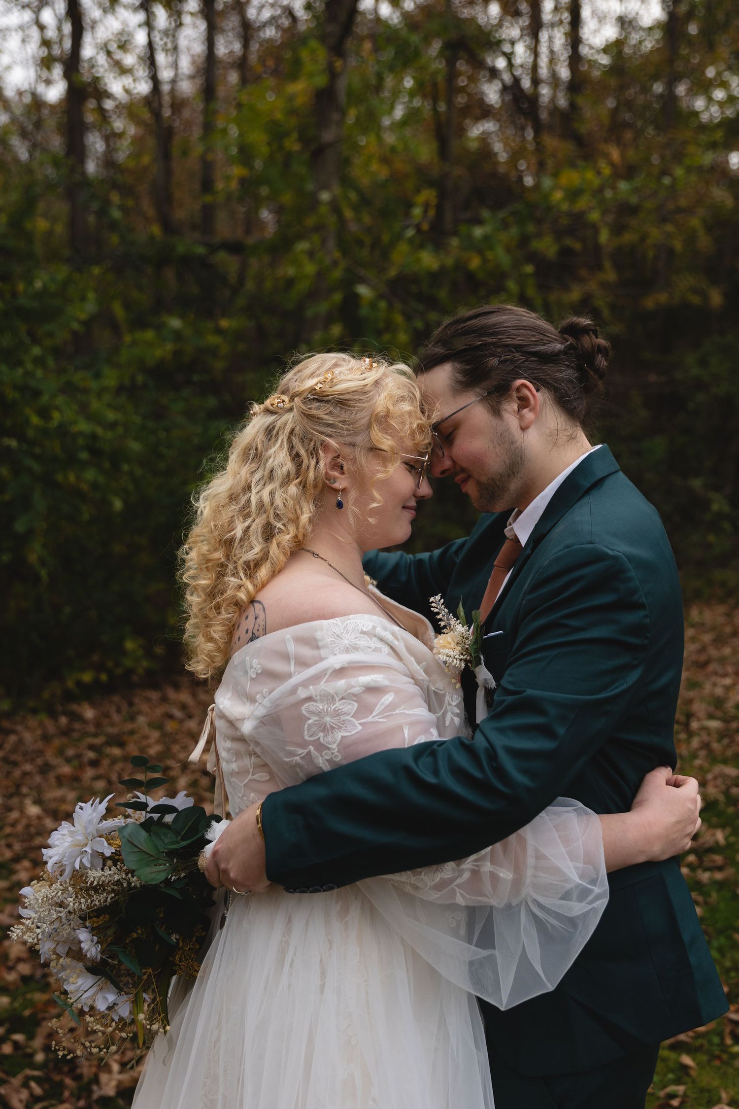 A tender embrace between newlyweds surrounded by autumn leaves.