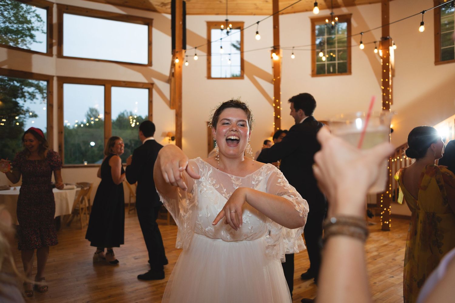 A joyful celebration on the dance floor during a wedding reception in a wooden venue.