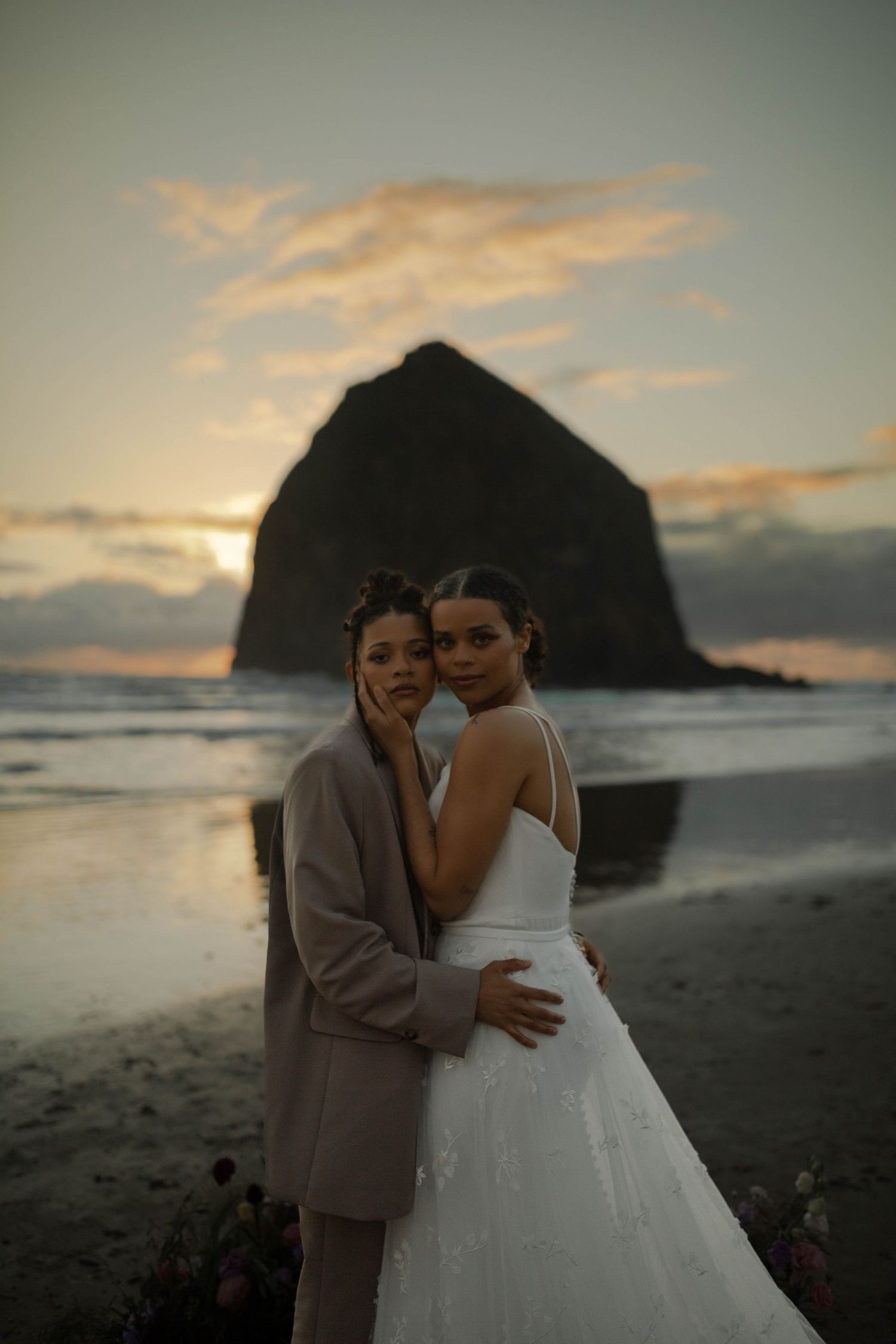 A sunset beach wedding portrait with the iconic Haystack Rock creating a dramatic backdrop.