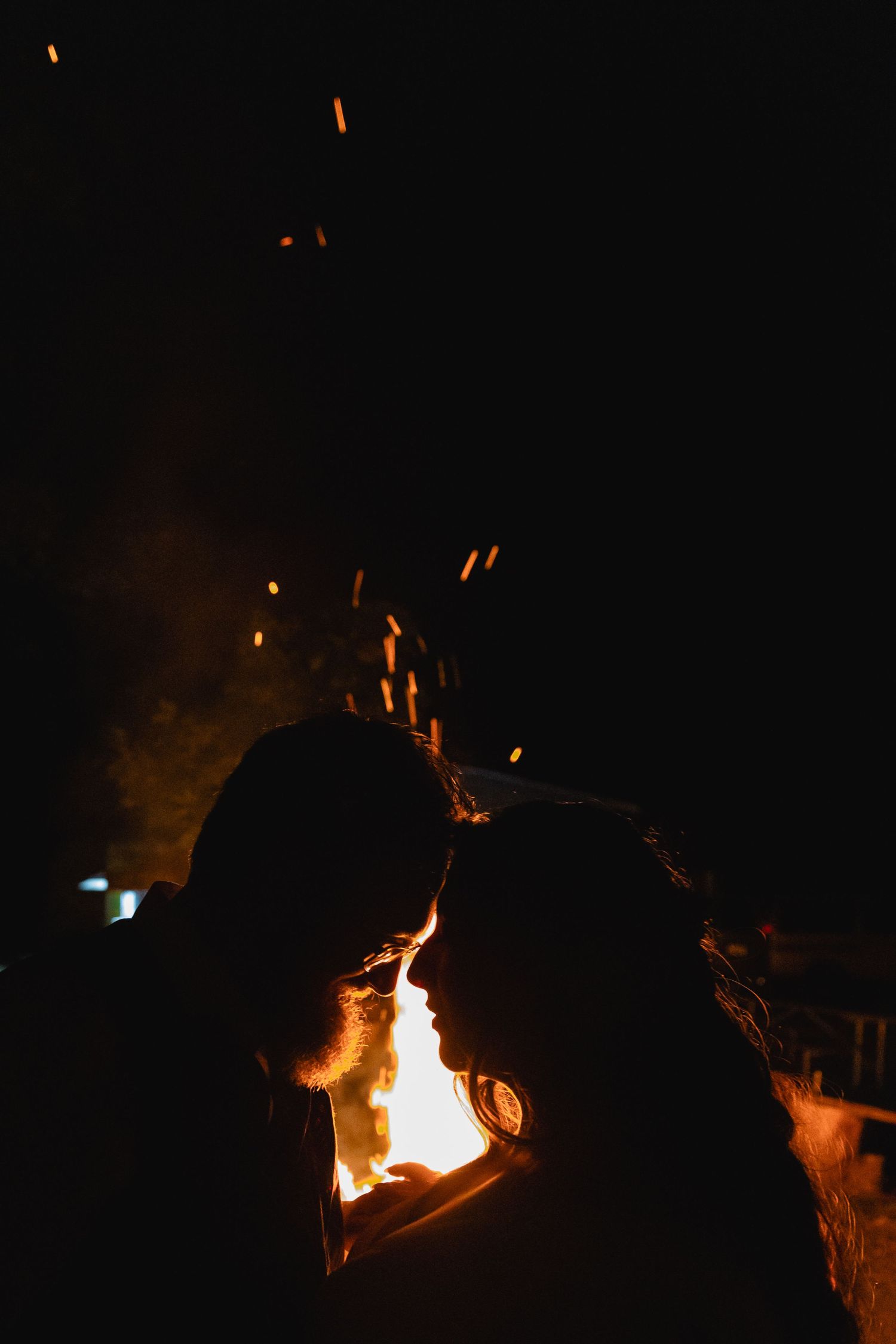 Romantic silhouettes against a glowing fire at night creating an intimate atmosphere.