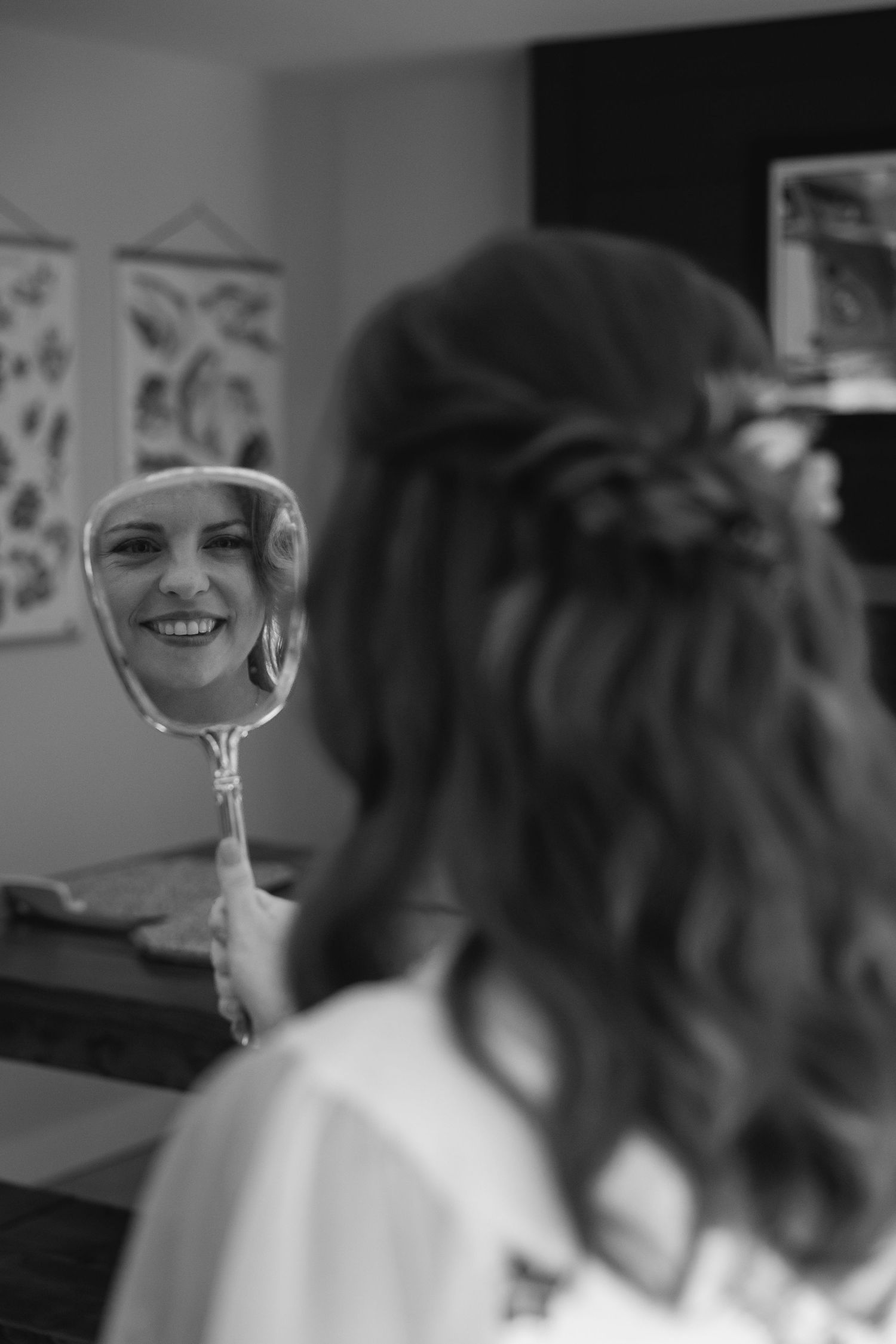 Black and white image showing a reflection in a handheld mirror against a blurred background.